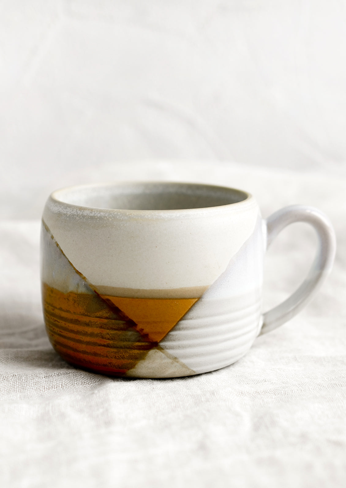 A mug with mix of brown and white glazes forming geometric pattern.