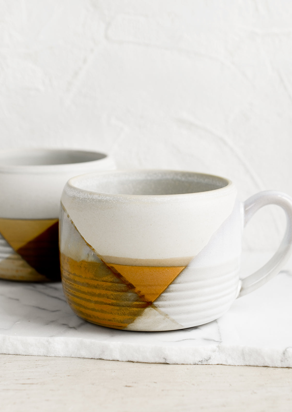 A mug with mix of brown and white glazes forming geometric pattern.