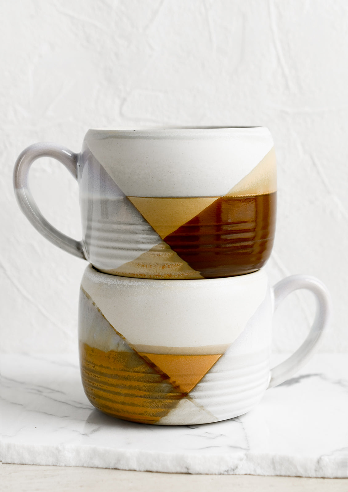 A mug with mix of brown and white glazes forming geometric pattern.