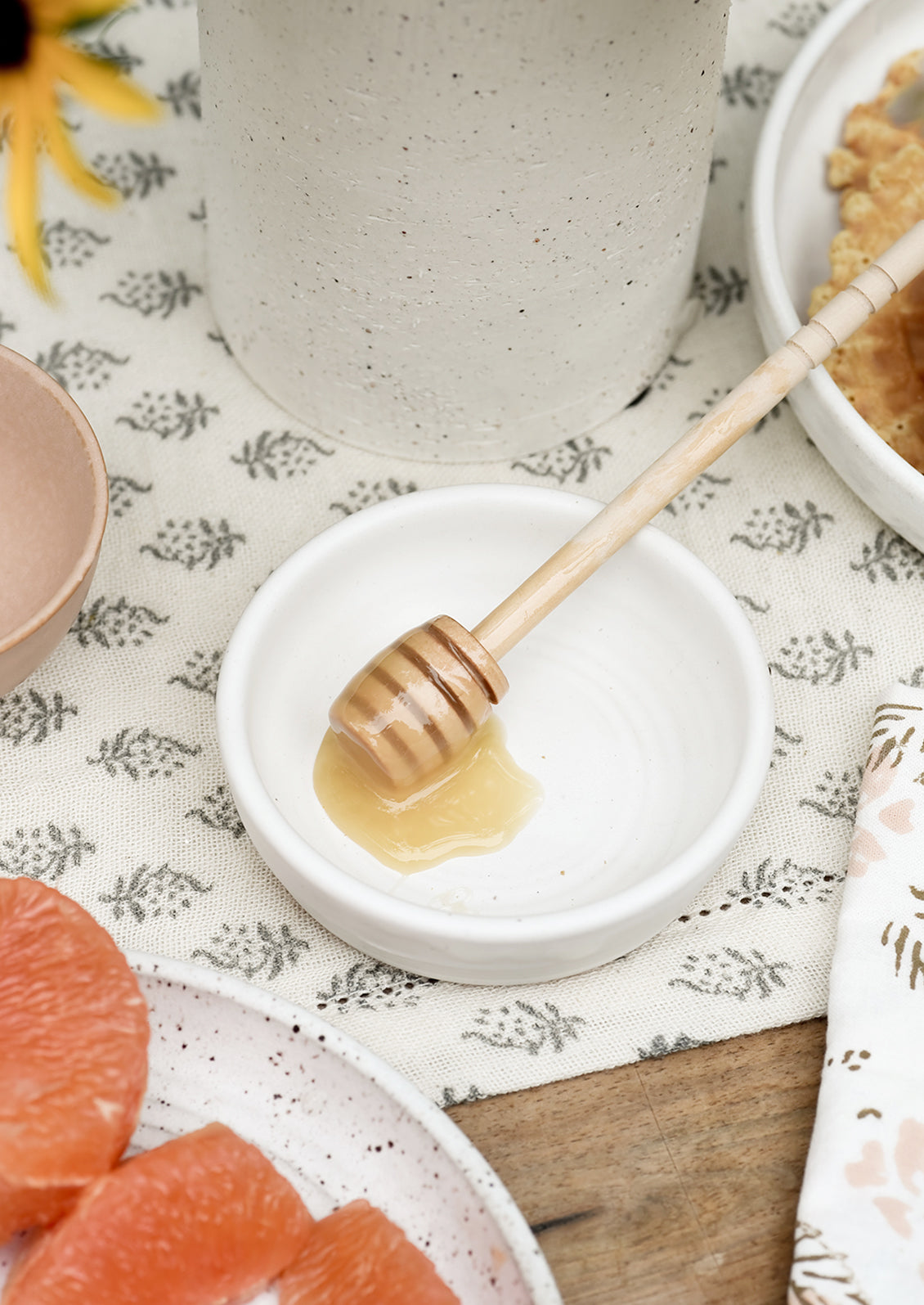 A small white ceramic bowl with honey dipper.