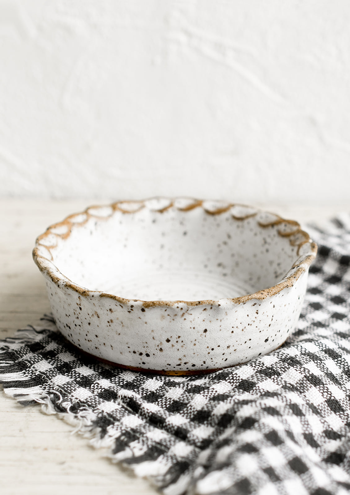 A small ceramic bowl with pinched rim in speckled white glaze.