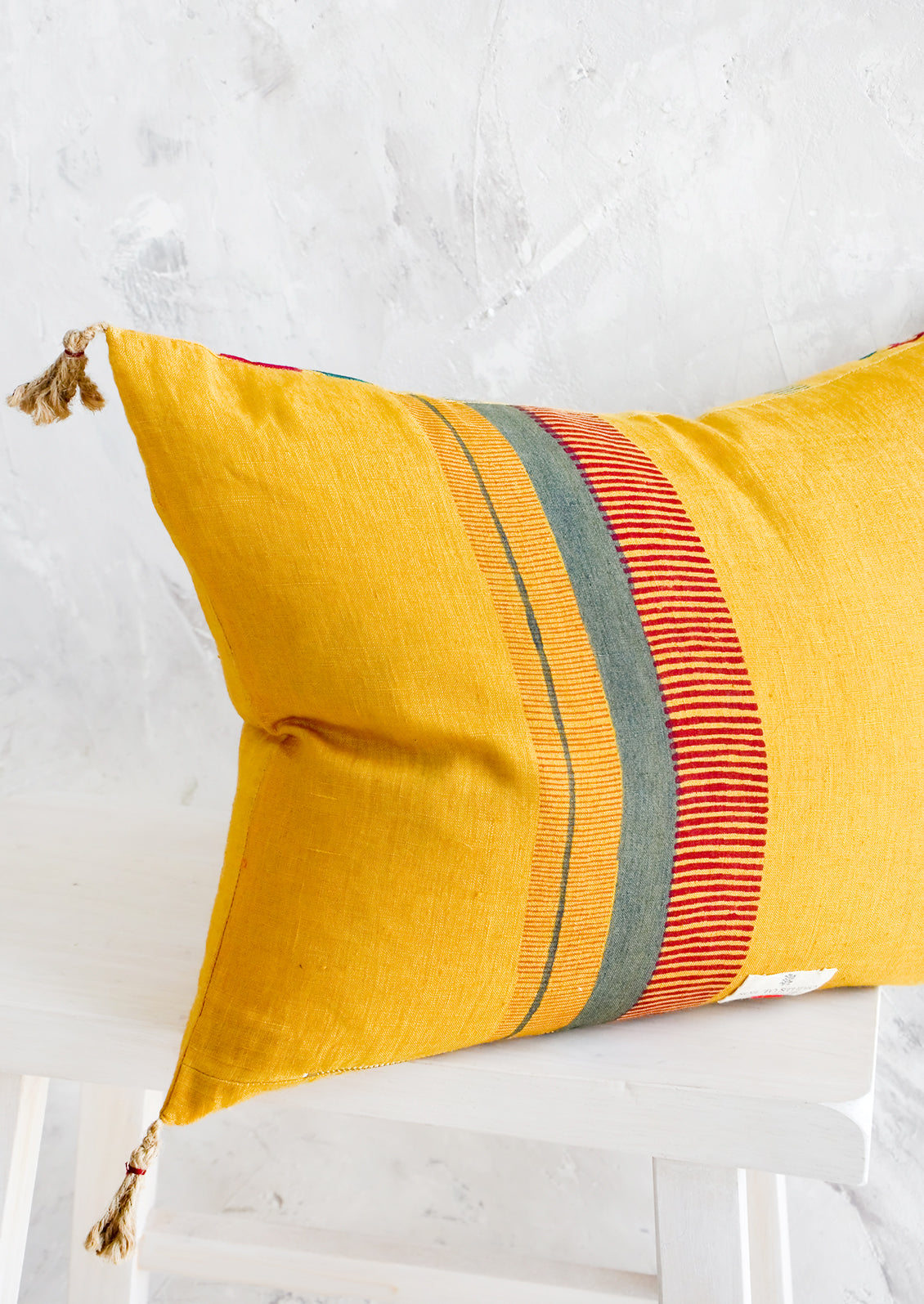 Back of lumbar throw pillow in mustard with block print stripe detail in red and green