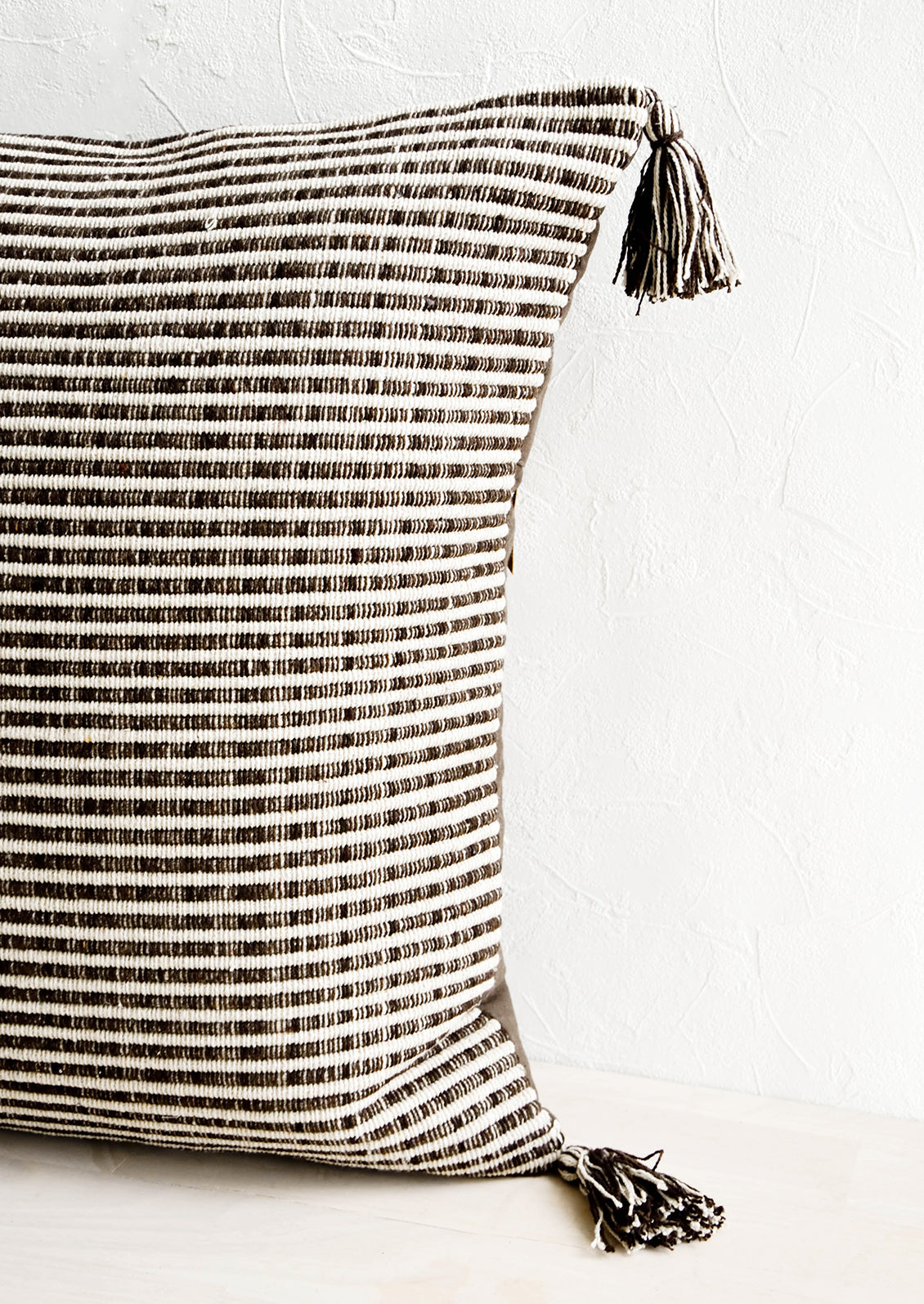 Textured, striped woven cotton pillow in dark brown and ivory with matching tassels at corners