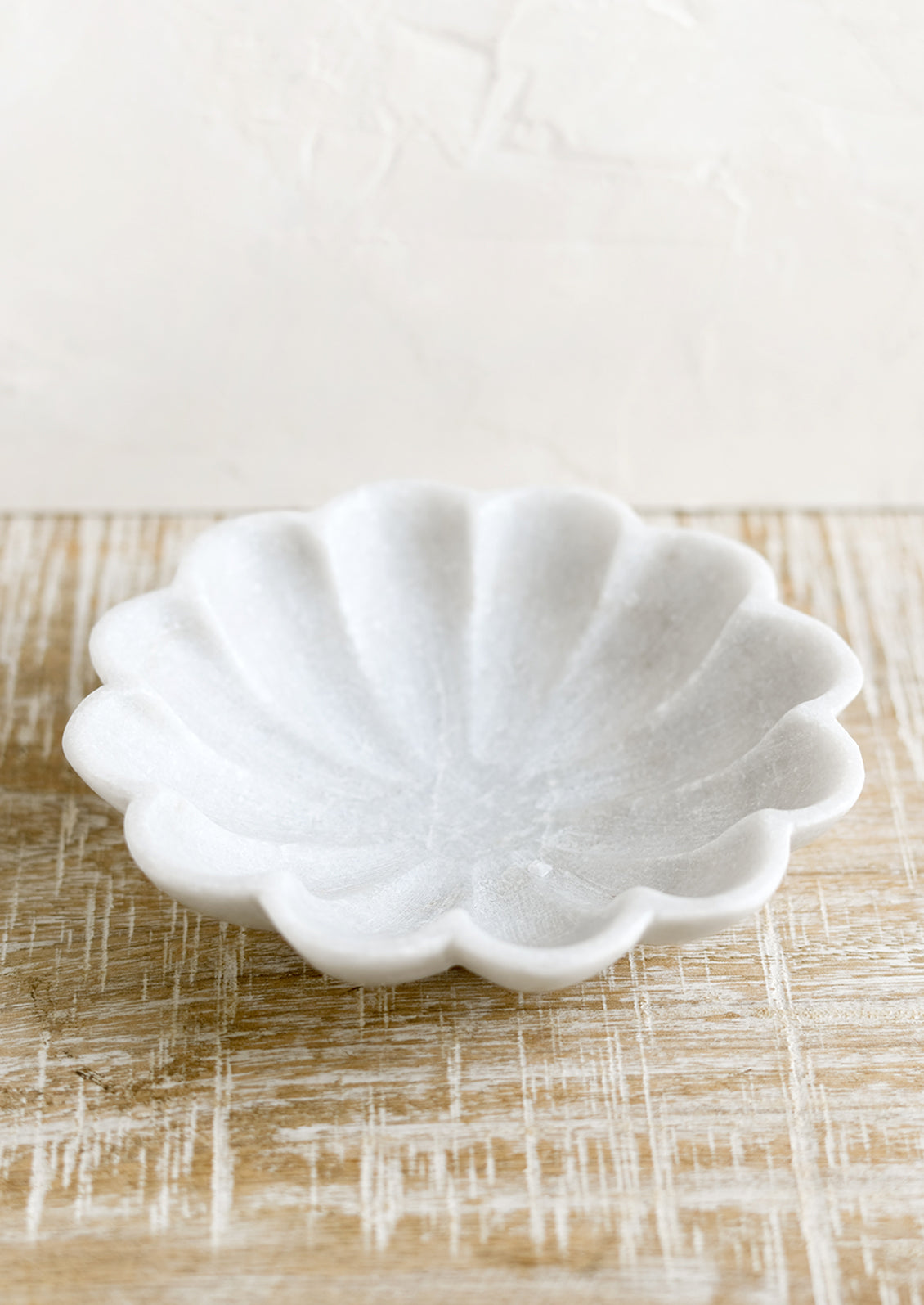 A shallow marble dish with curvy scalloped design.