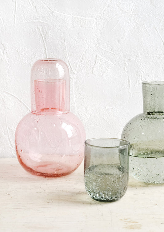 Translucent glass drinking carafes in pink and grey.