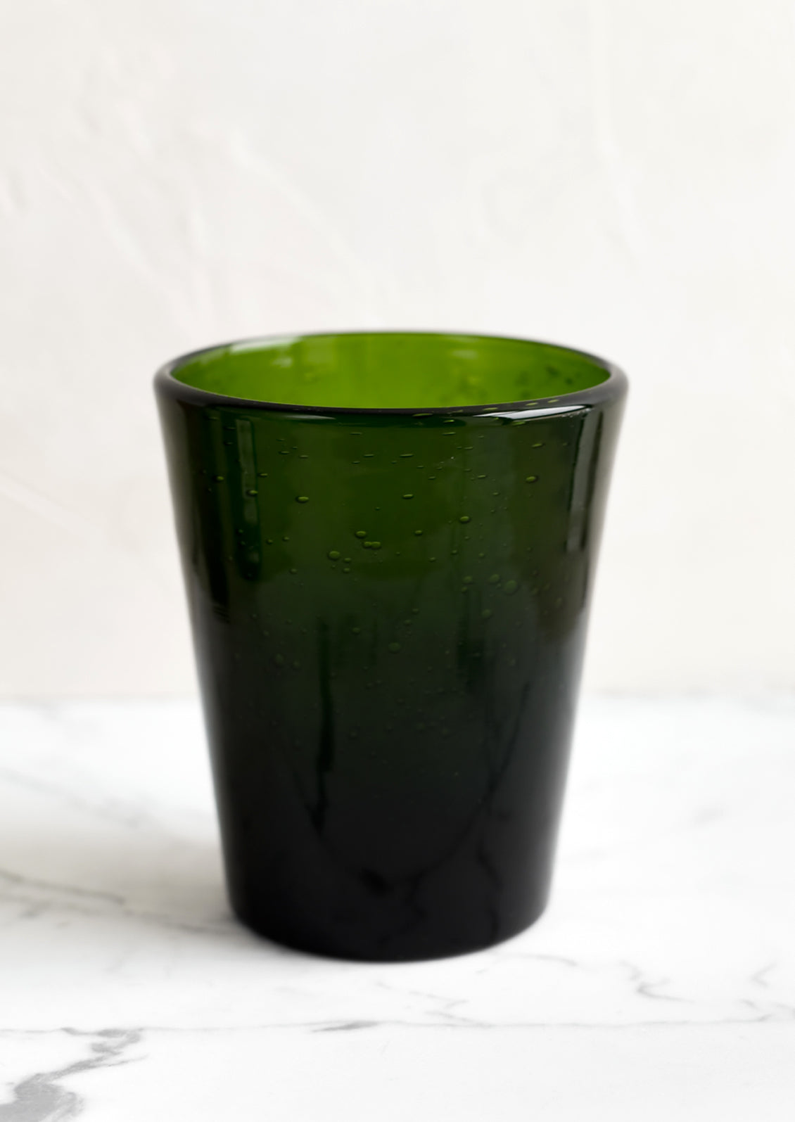 A glass tumbler cup in green seeded glass.