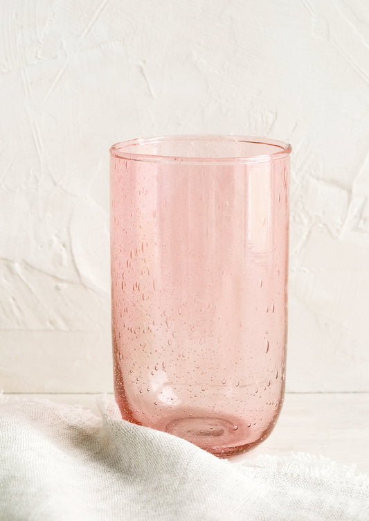 A tall glass tumbler in seeded pink glass.