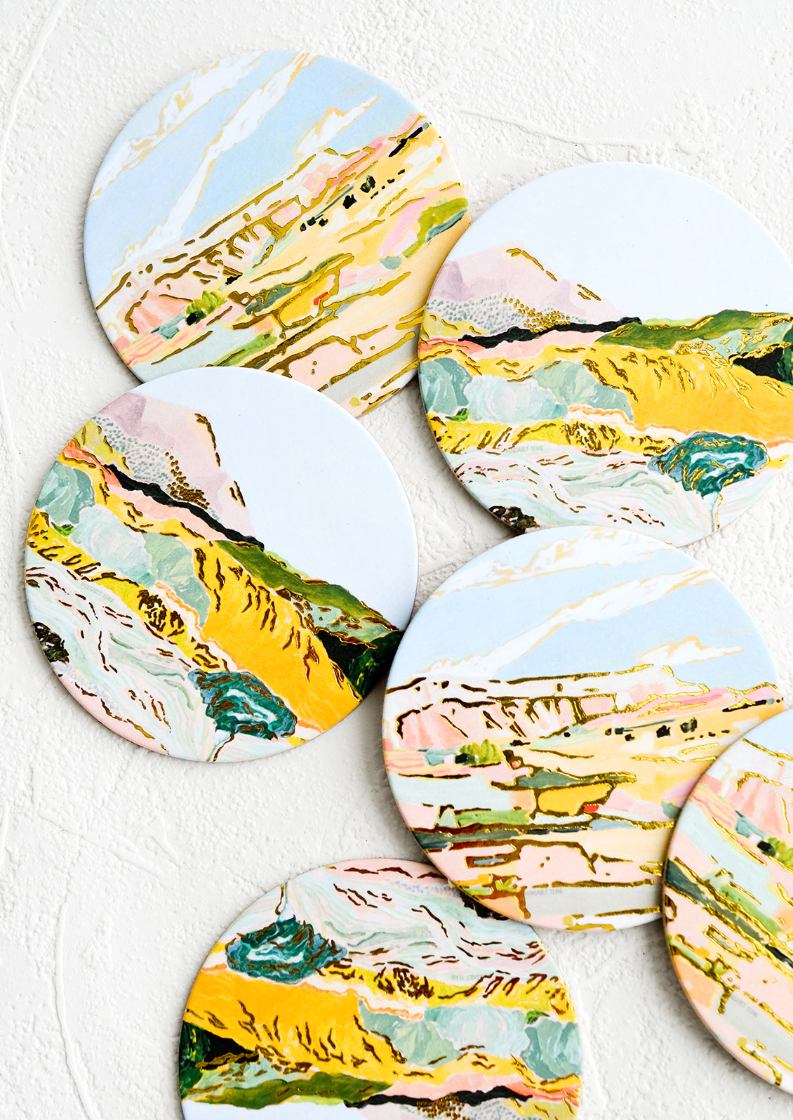 A set of graphic print coasters with pastel imagery of mountains and cliffs.