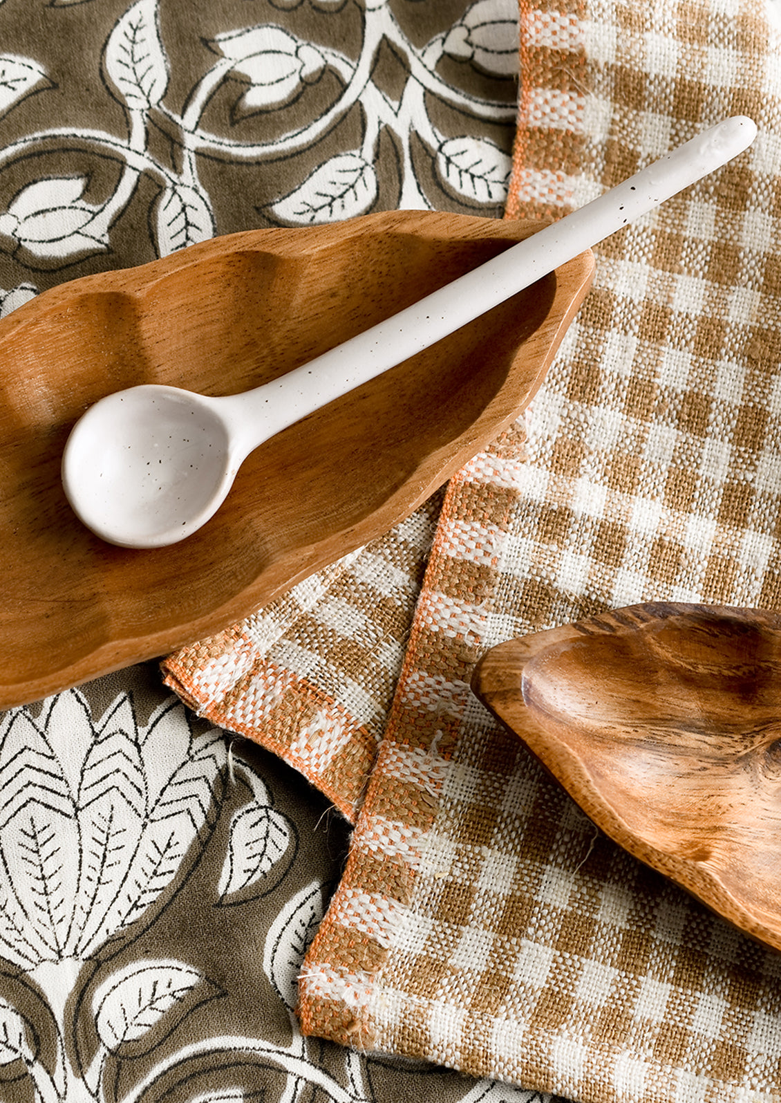 Wooden dishes styled with textiles and spoon.