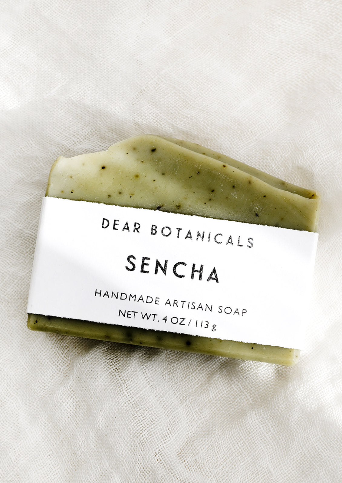 A bar of soap in sencha scent (green with black speckles).