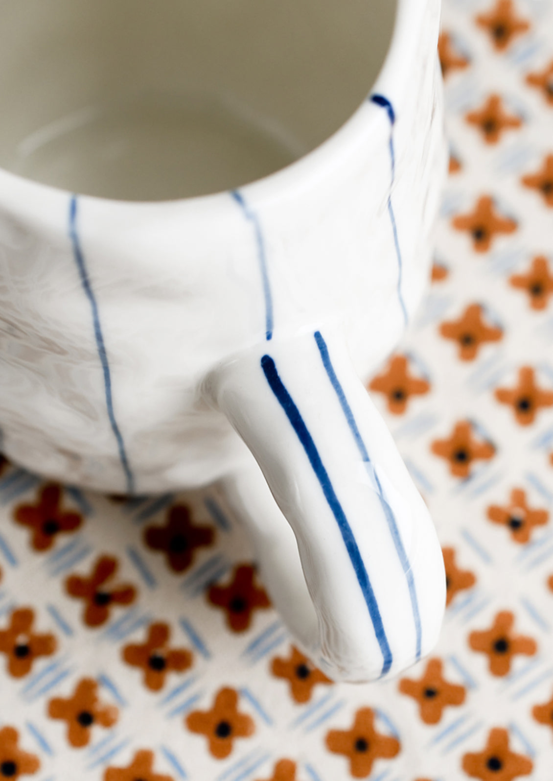 A pinched white mug with vertical thin blue stripes.