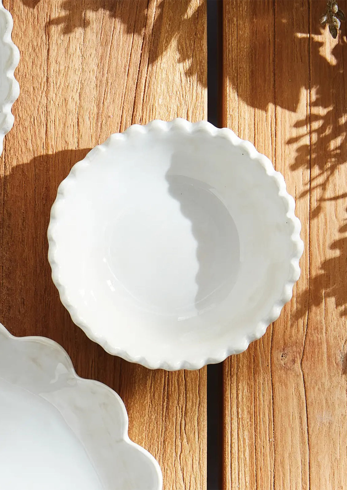 A small ceramic bowl with scalloped rim in white.