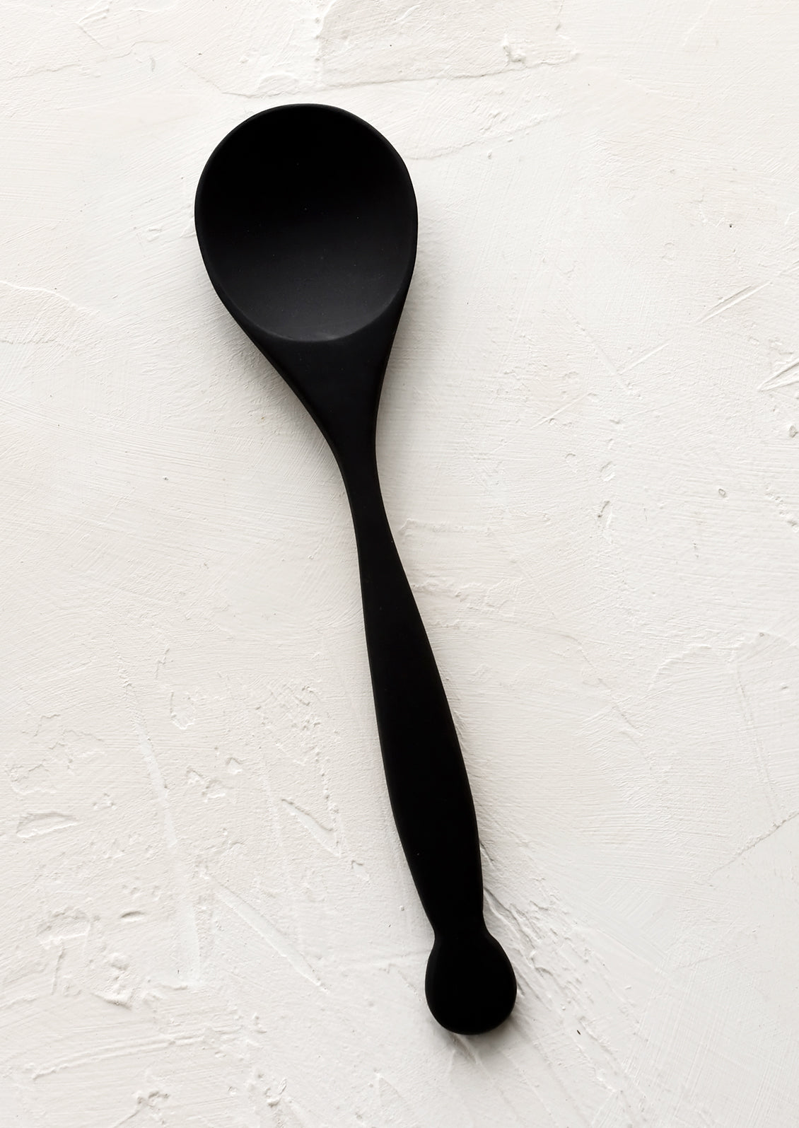 A carved black wooden spoon with decoratively curved handle.