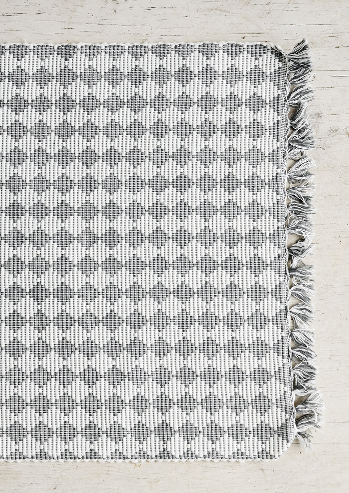 A grey and white placemat with triangular checkered pattern.