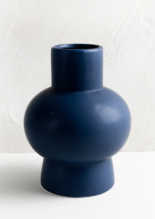 A navy blue sculptural ceramic vase.