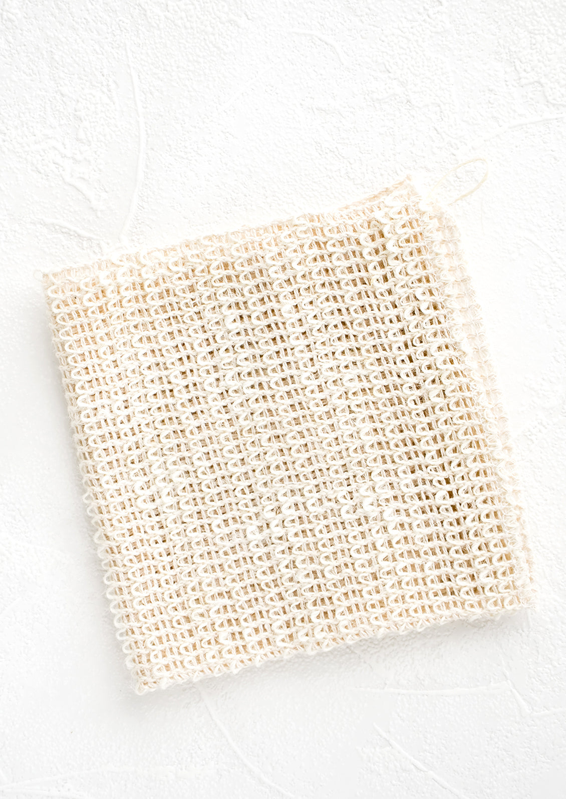 A folded washcloth made from natural sisal with a hanging loop at one corner.