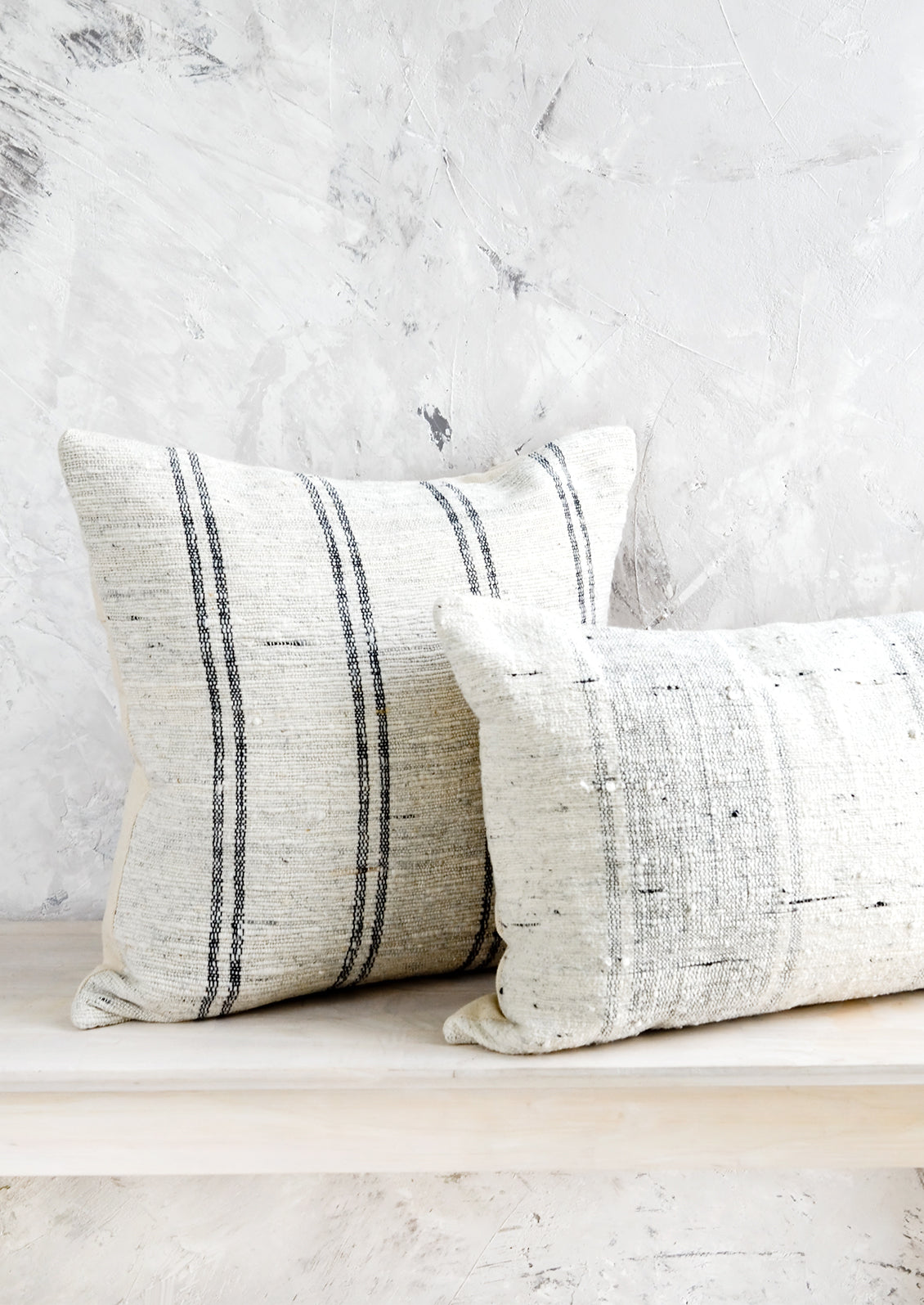 Square and lumbar throw pillows in white slub fabric with grey or black stripes.