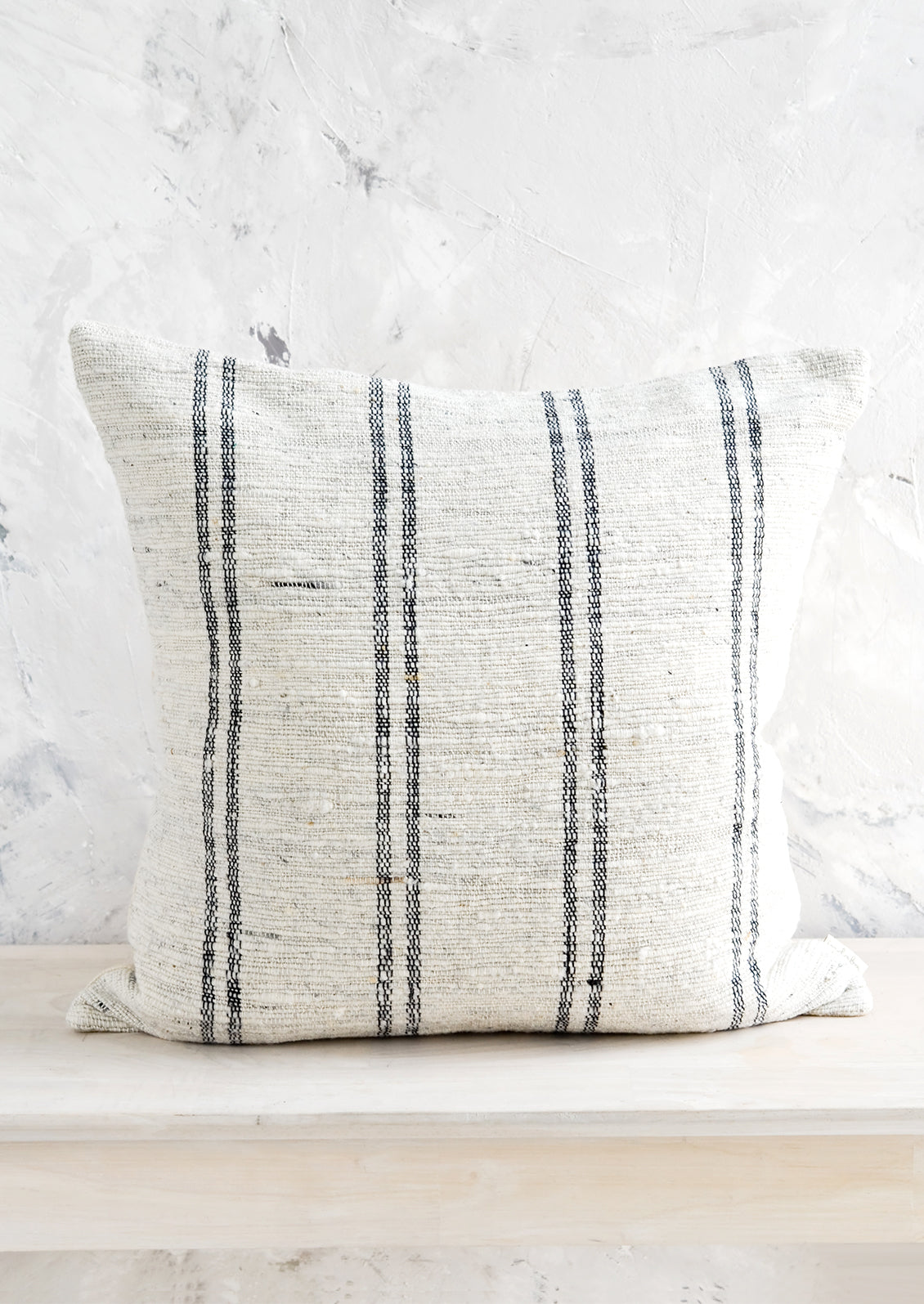 Square throw pillow in textured cotton slub fabric with dark vertical stripes.