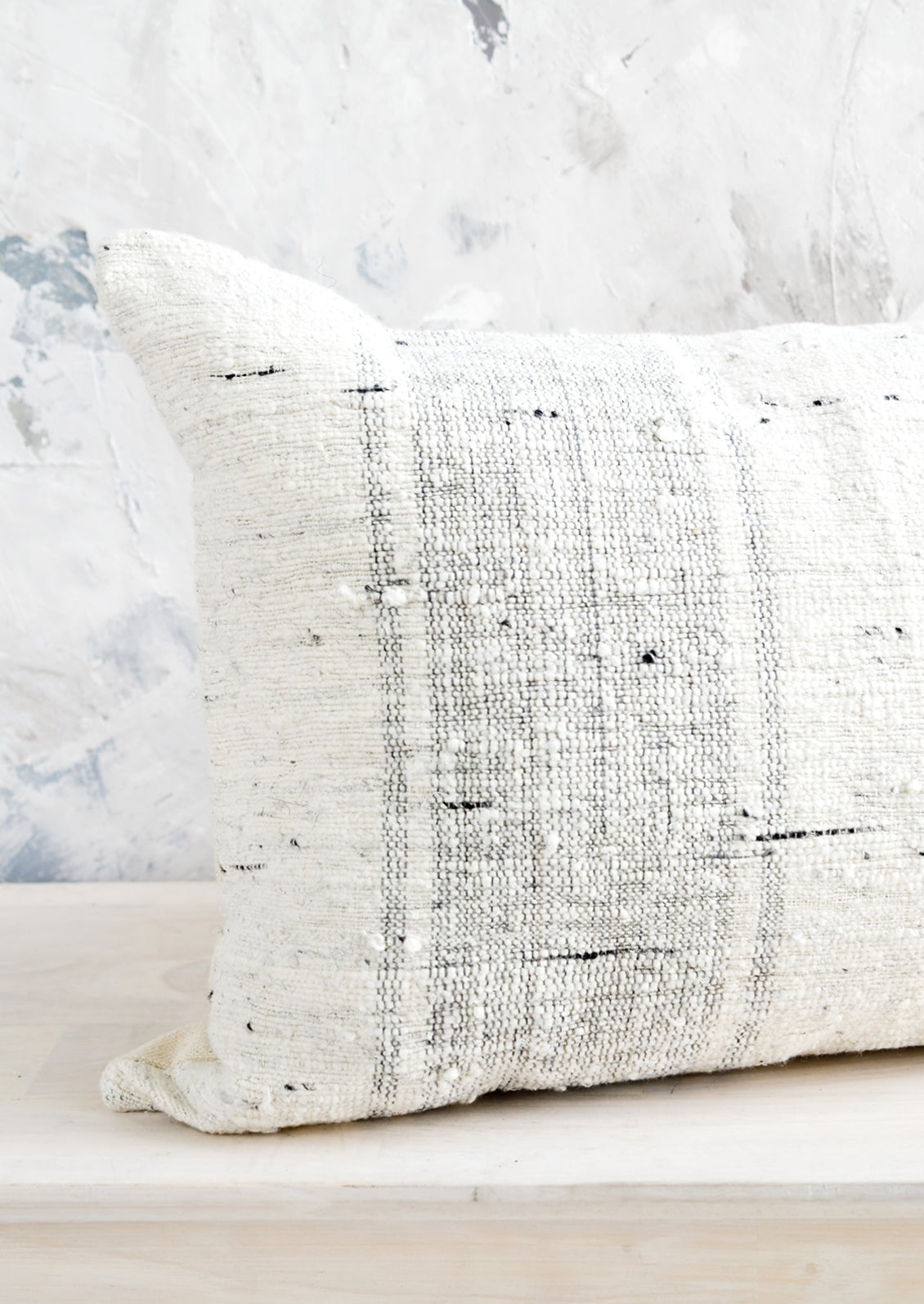 A throw pillow in heavily textured slub fabric in white and grey.