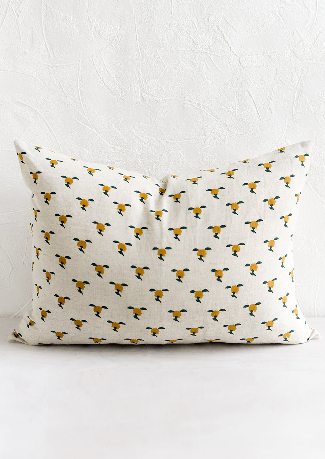 A block printed lumbar pillow with yellow and green floral motif.