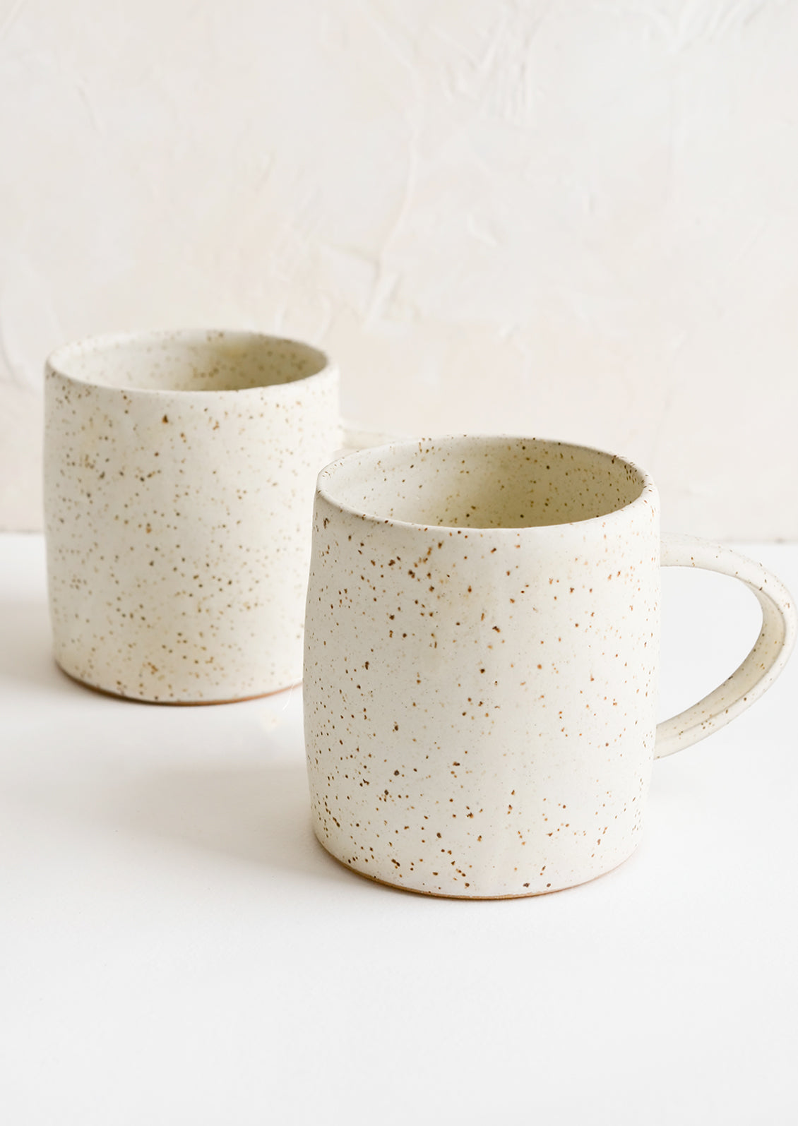 A pair of speckled white coffee mugs.