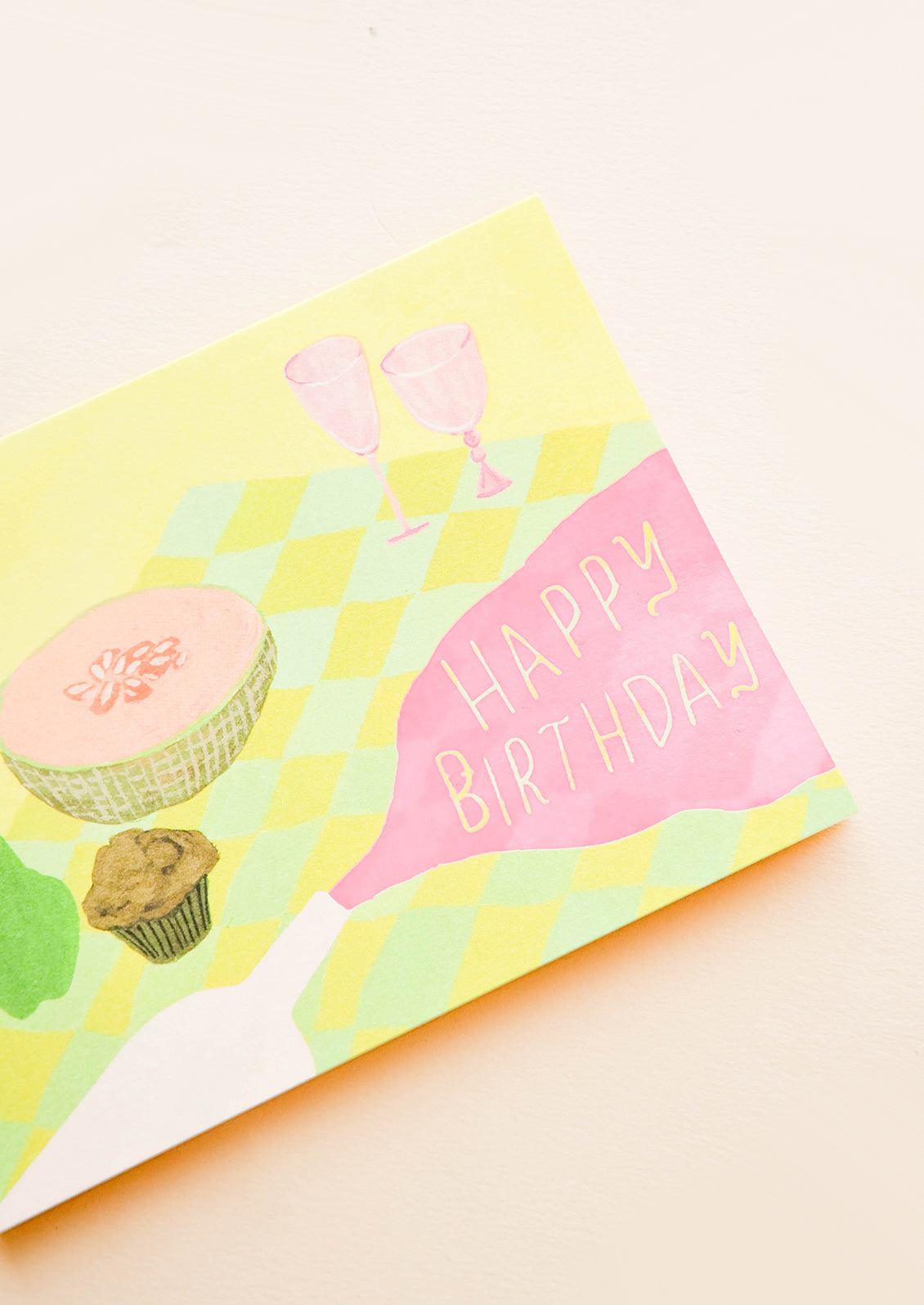 Greeting card with picnic setting, neon pink spilled wine puddle has letters reading "Happy Birthday"