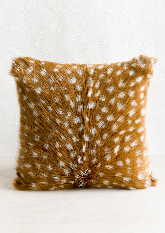 A goat fur pillow in sable brown with white spots throughout.