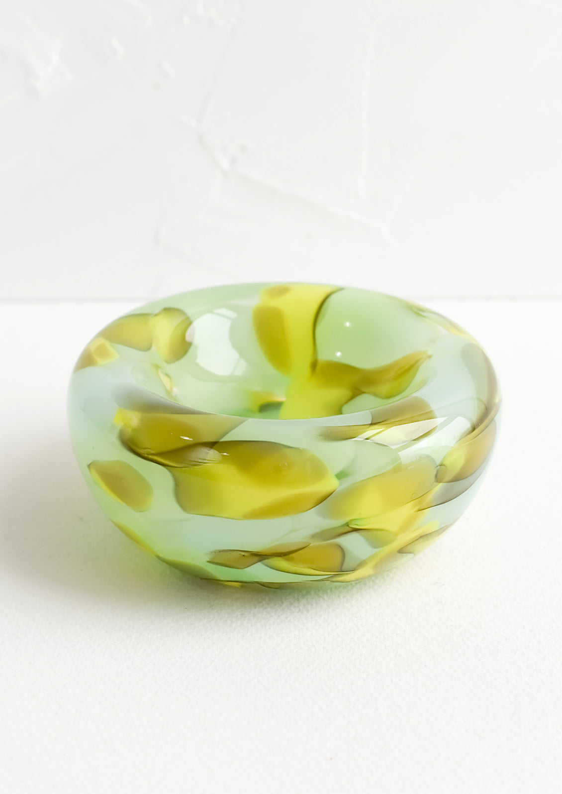 A decorative glass bowl with multicolor mint and chartreuse pattern.