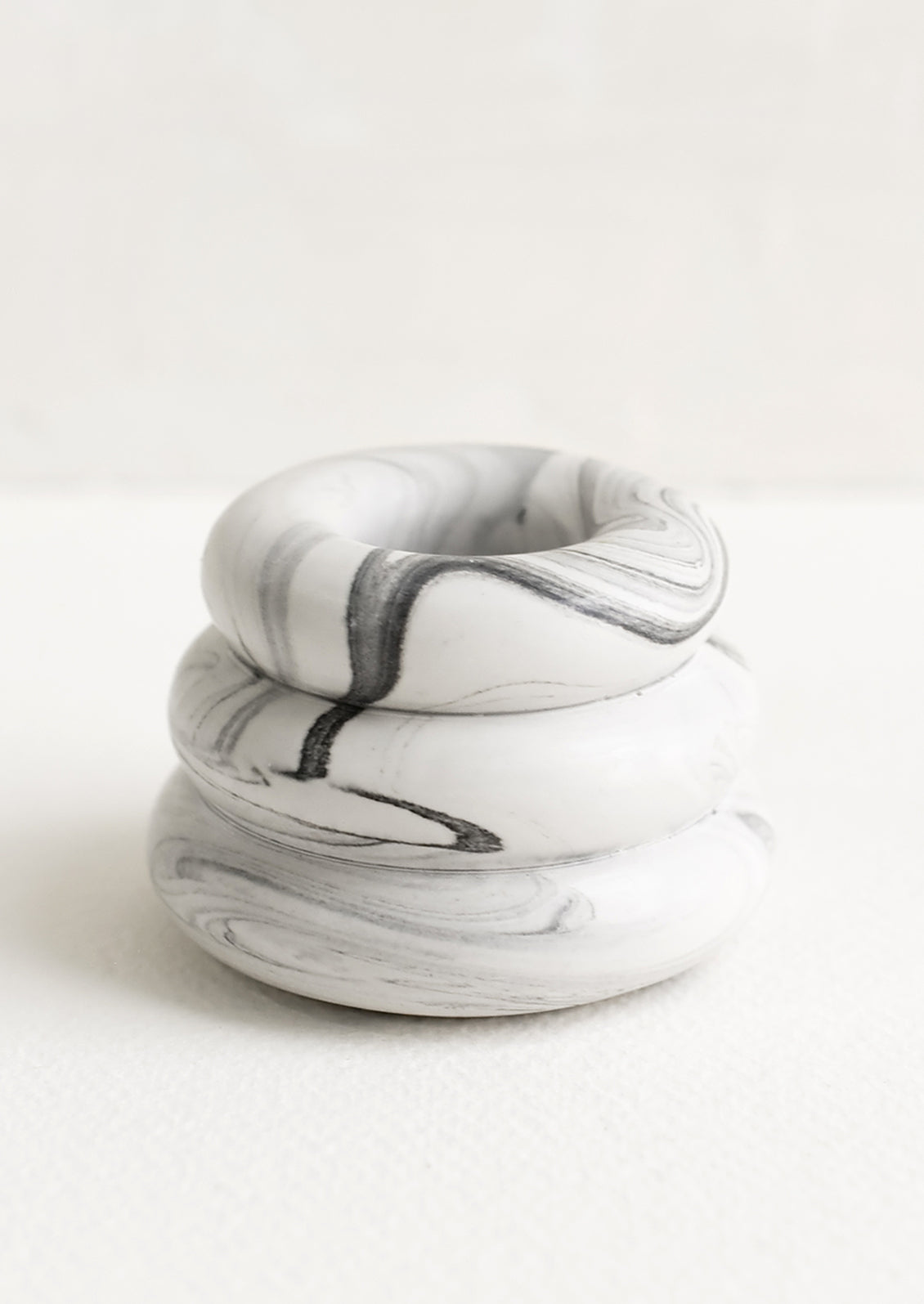 A taper candle holder with 3-layer stacked donut shape in grey and white marble.