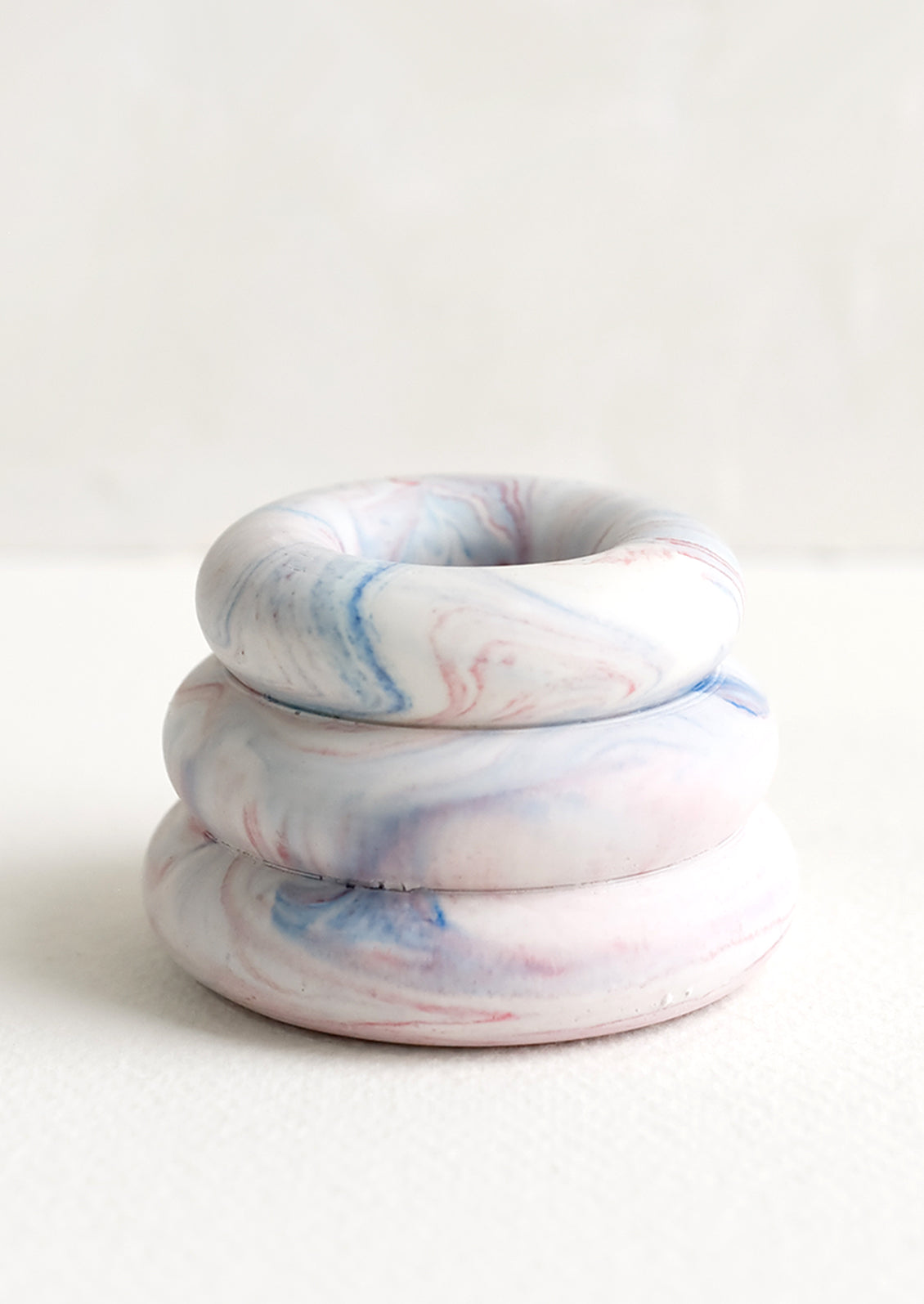 A taper candle holder with 3-layer stacked donut shape in blue and red marble.