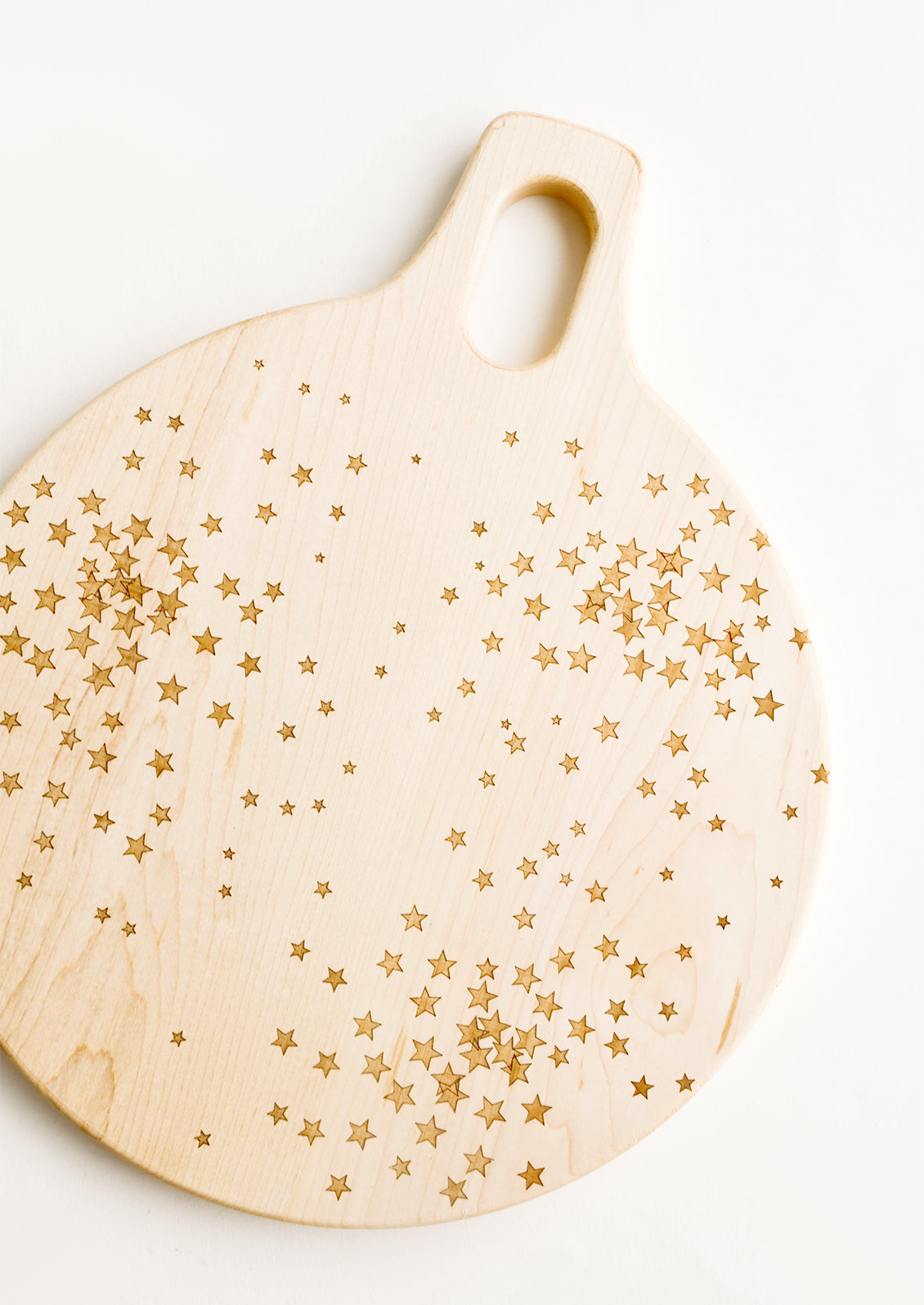 Round paddle-style cutting board in maple wood with scattered star pattern