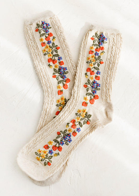 A pair of oatmeal colored socks with primary color strawberry print.