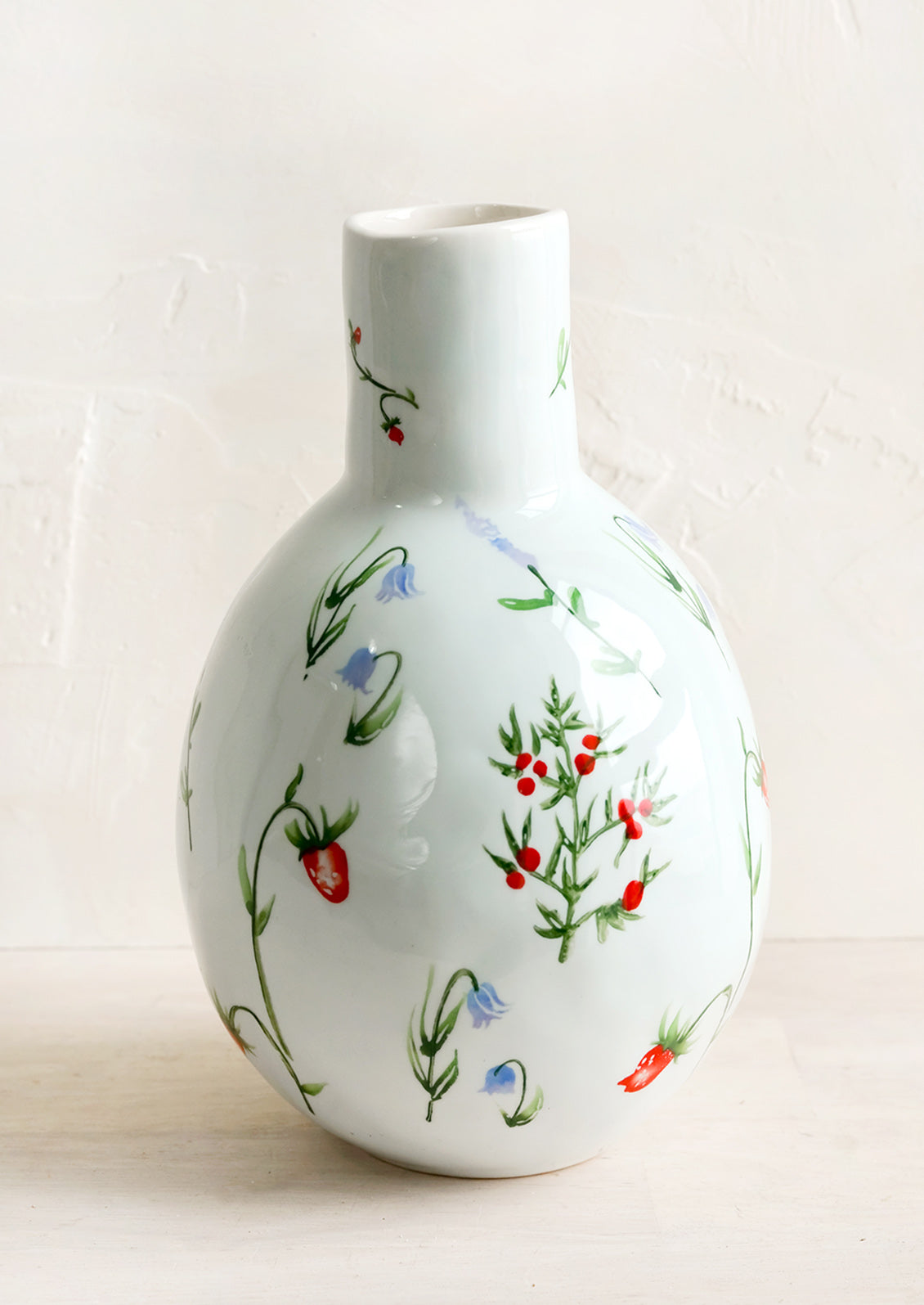 A ceramic vase with bulbous base and narrow top with painted floral print.