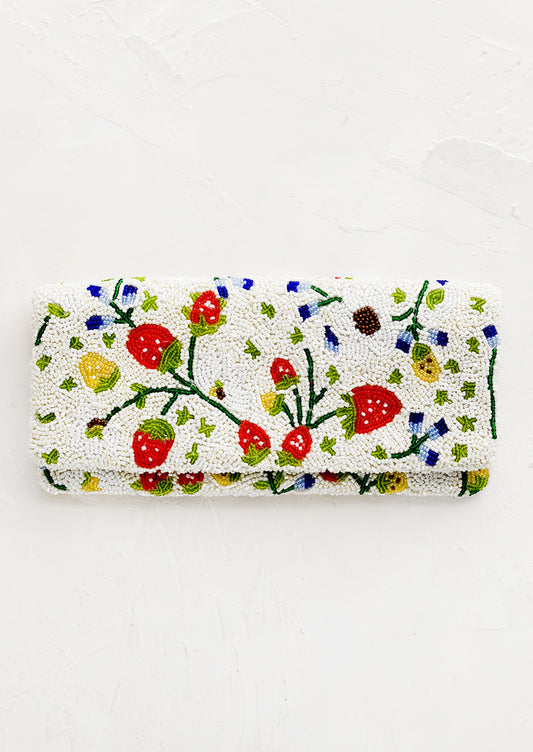 A rectangular foldover beaded clutch in white with multicolor strawberry pattern.