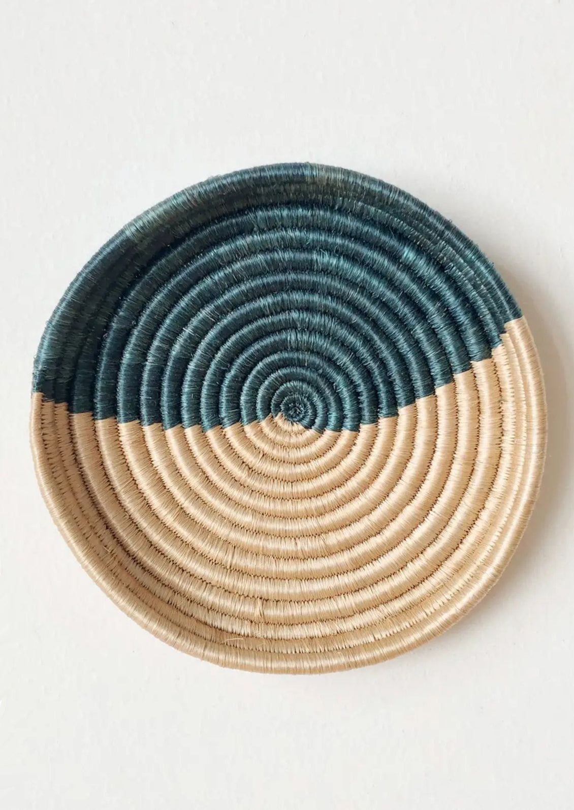 A round, shallow sweetgrass tray in beige and teal.