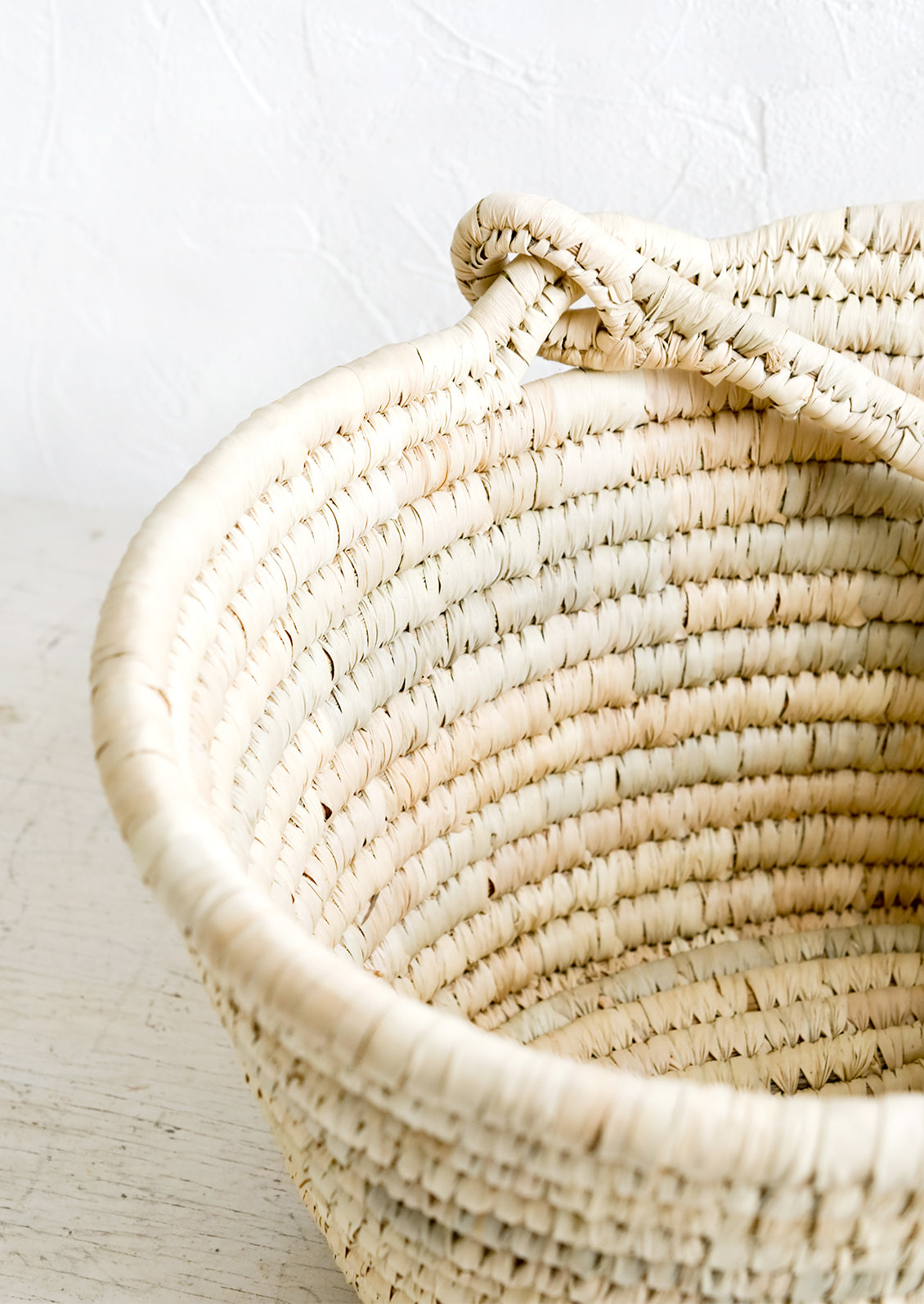 A swing-attached carrying handle on a natural straw basket.