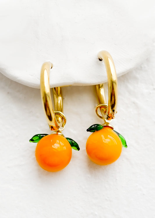 Gold huggie hoop earrings with glass tangerine charms.