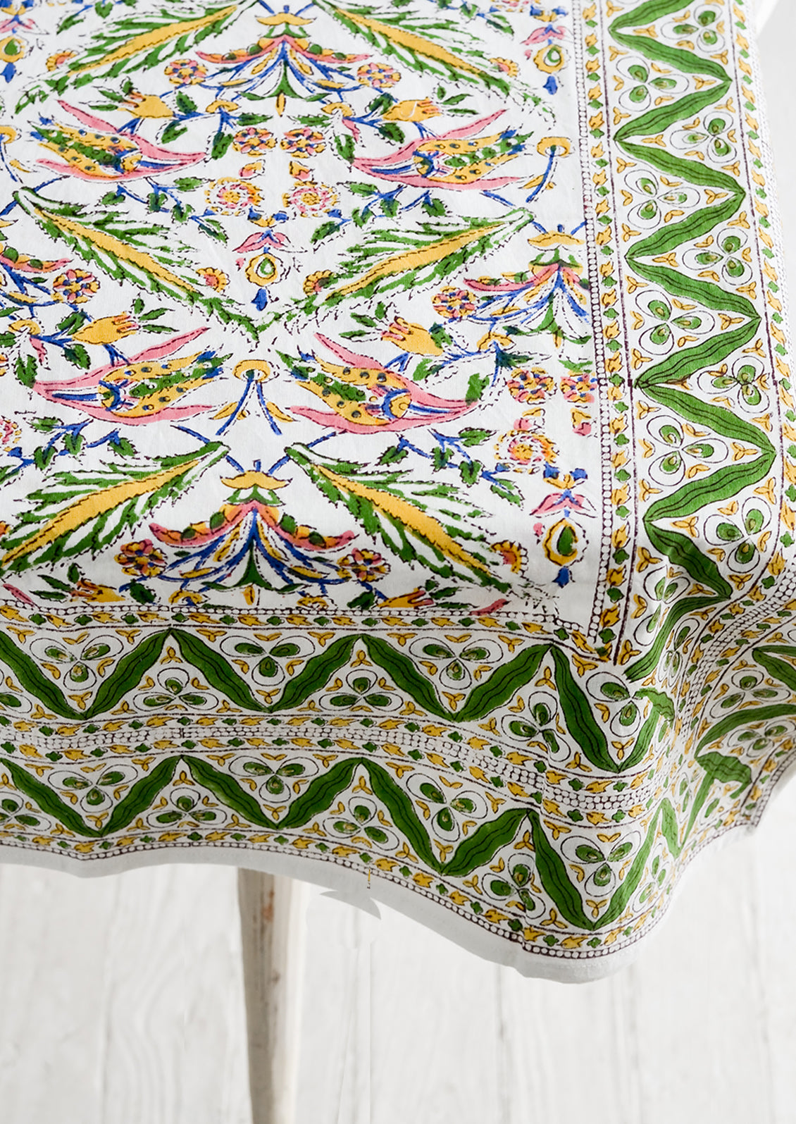 A block printed cotton tablecloth in vibrant green, pink and yellow floral pattern.