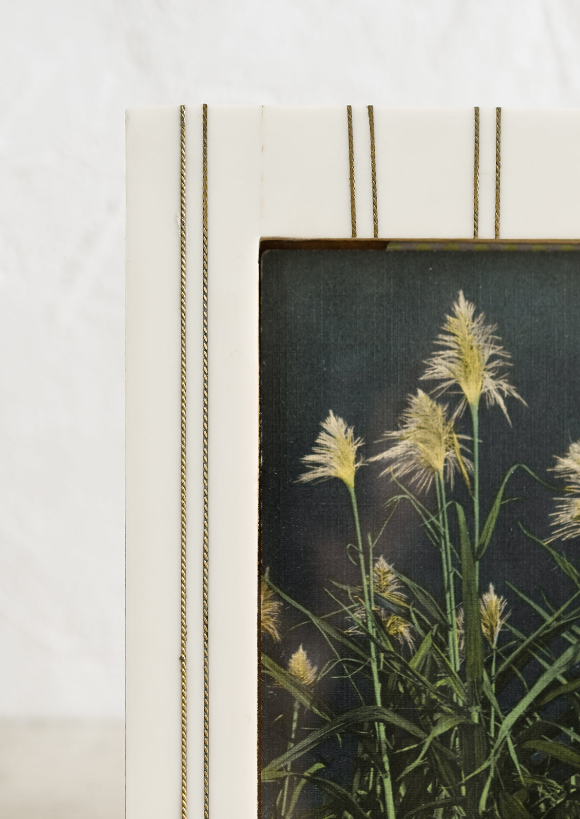 An ivory resin picture frame with vertical brass ticking stripe detail.