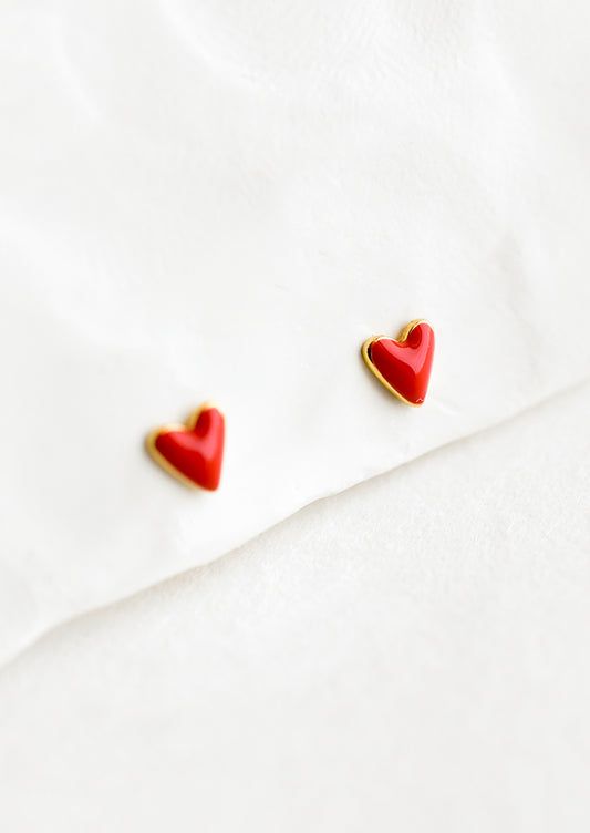 A pair of earrings in the shape of a tiny red heart.