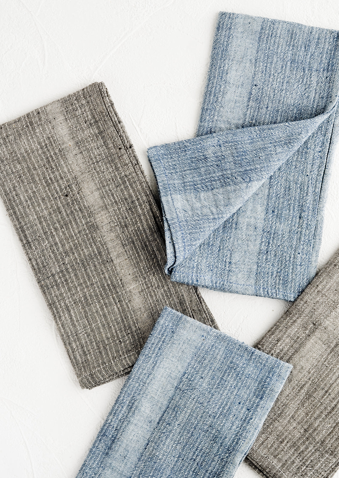 Fabric napkins in indigo and charcoal with textured tonal stripe pattern.