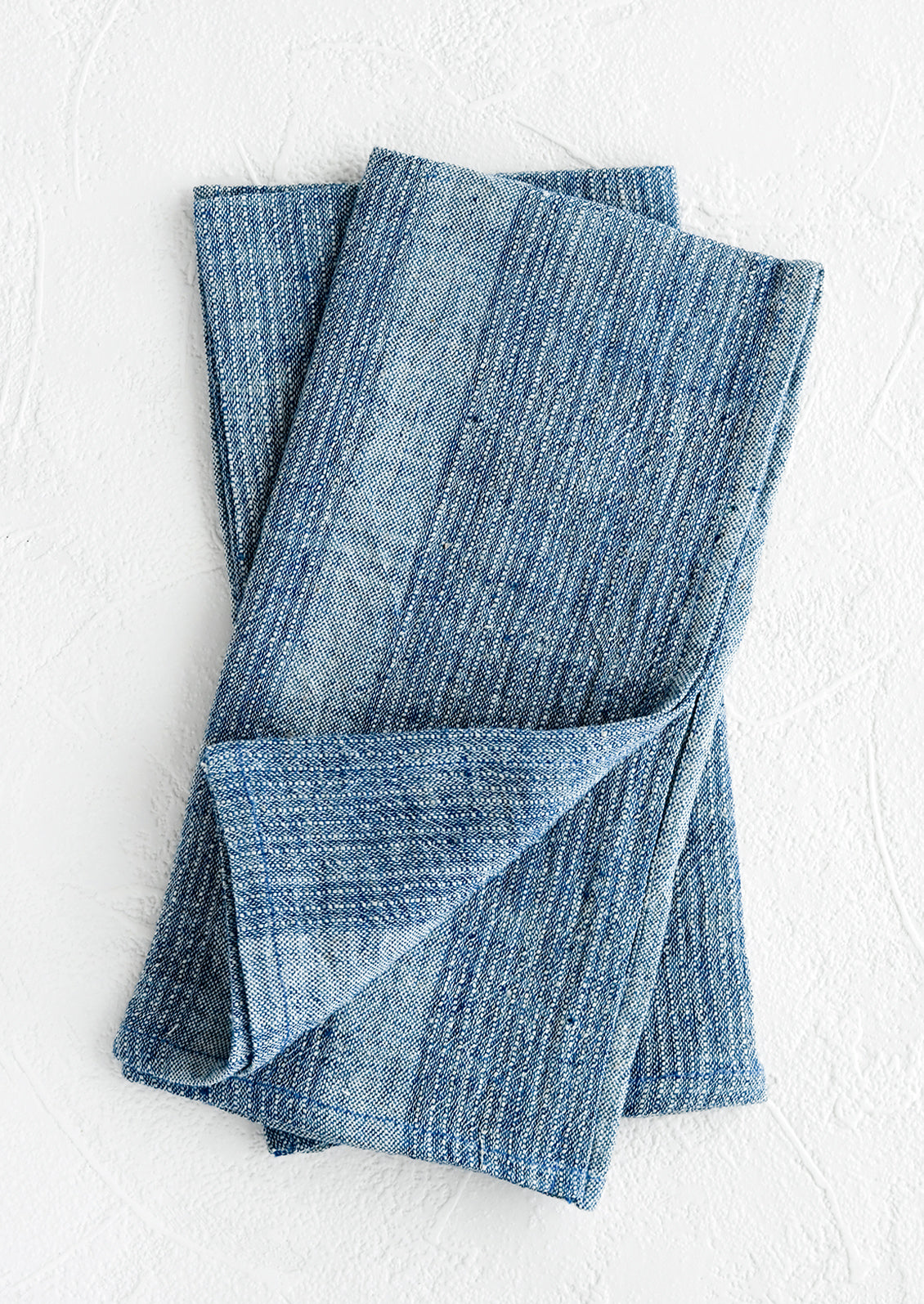 A pair of indigo fabric napkins with textured tonal stripe pattern.