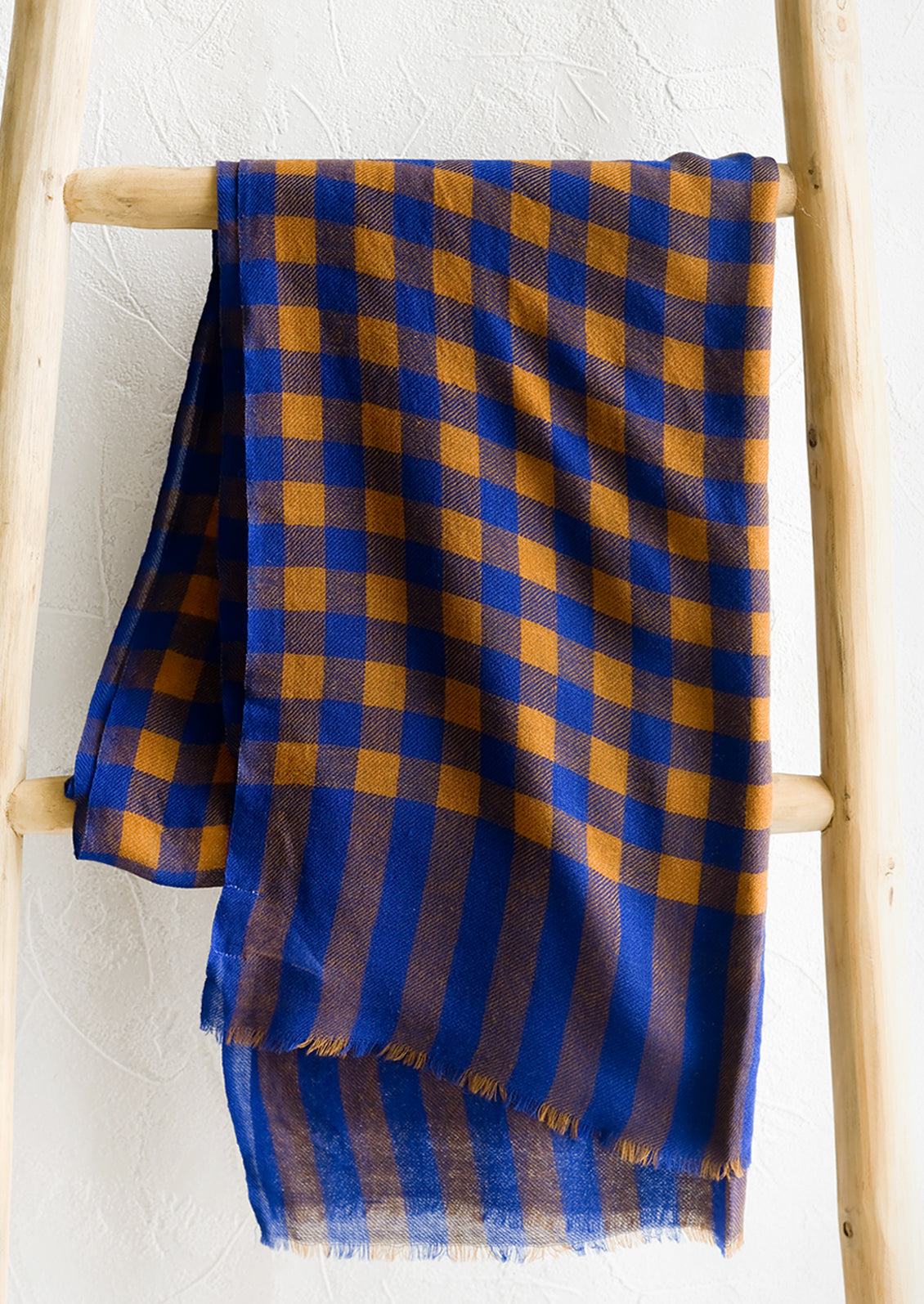 A lightweight woven wool scarf in blue and caramel gingham.