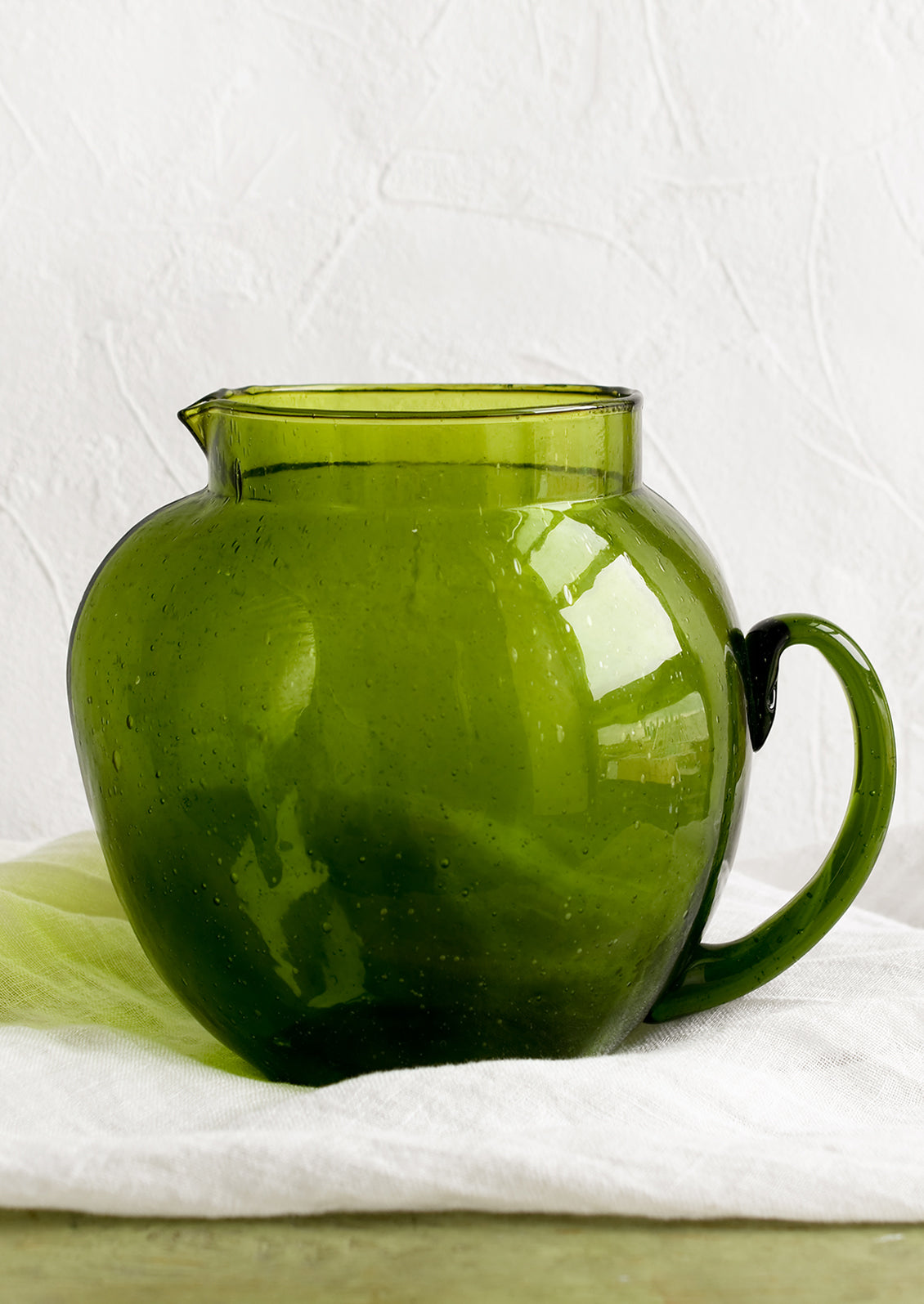 A green glass pitcher with large, rounded shape.