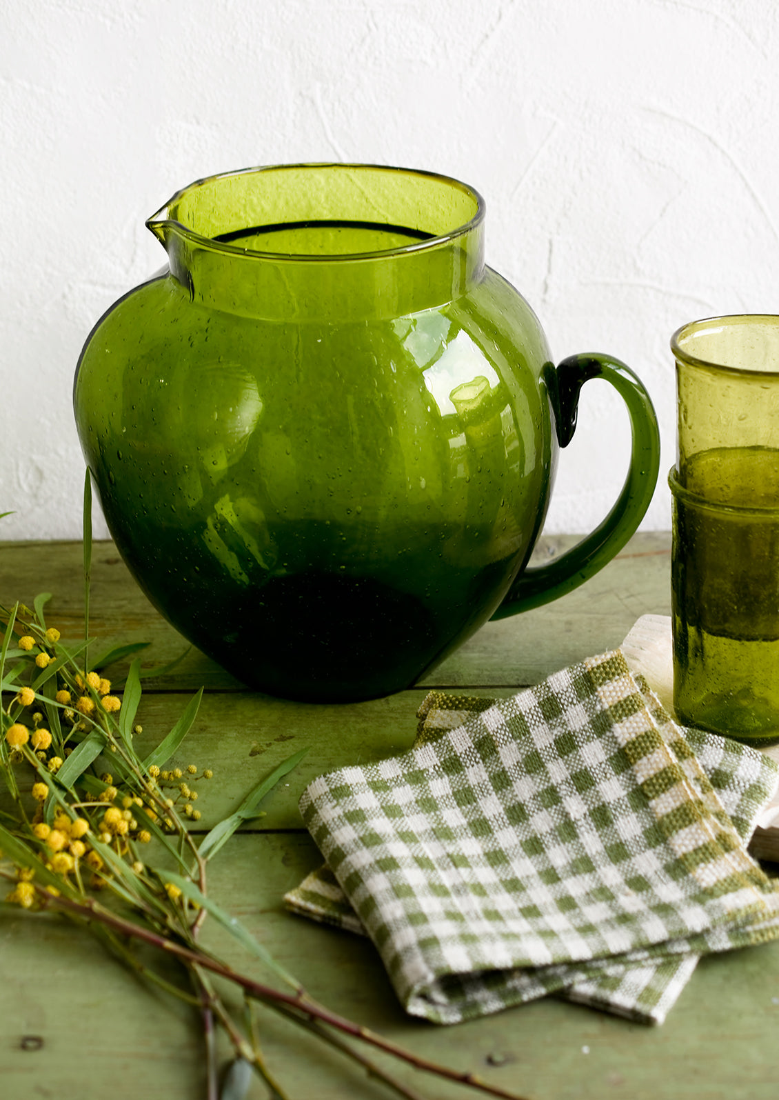 A green glass pitcher with large, rounded shape.