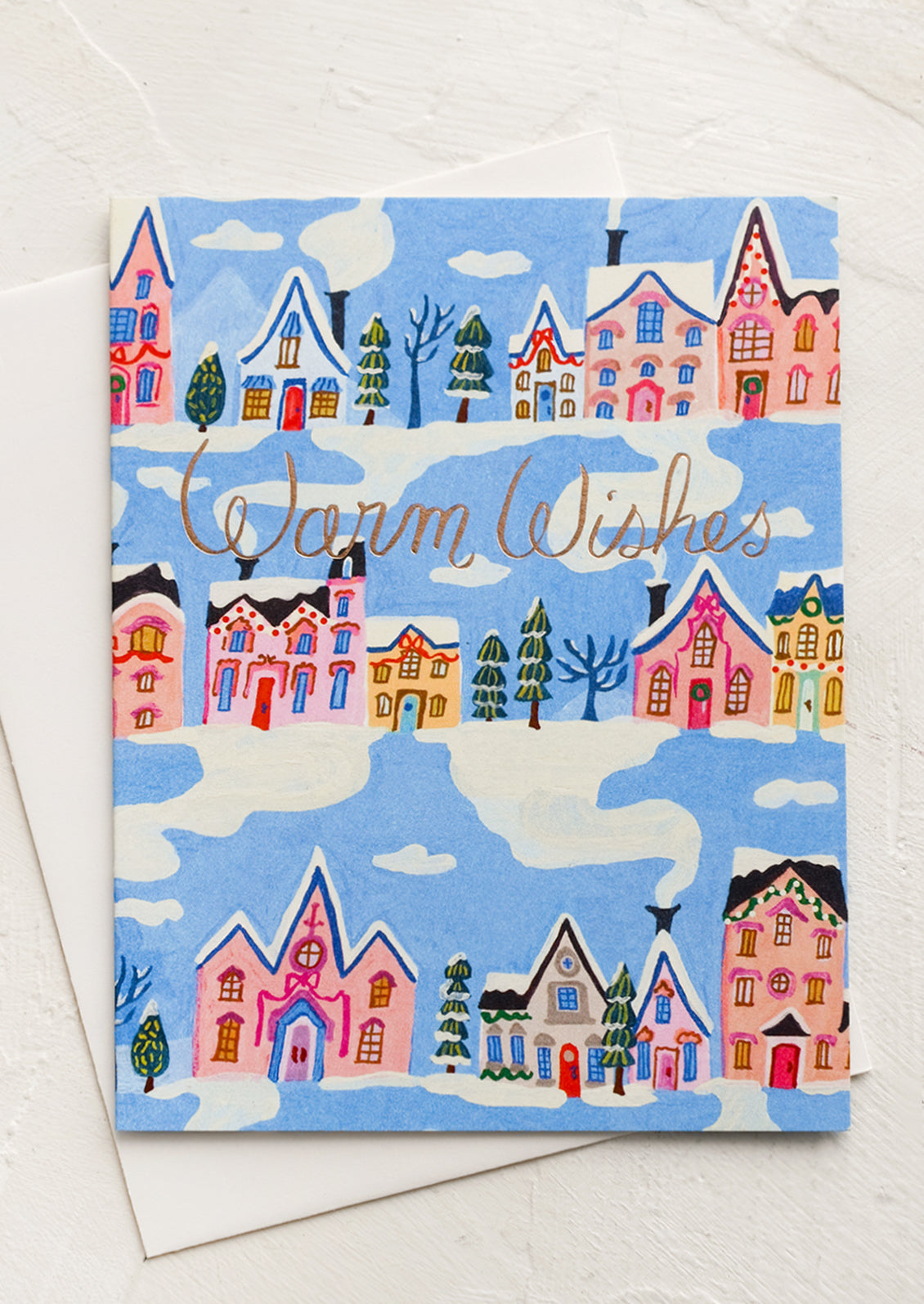 Greeting card with blue background and repeating rows of houses and trees. "Warm Wishes" written in copper script.