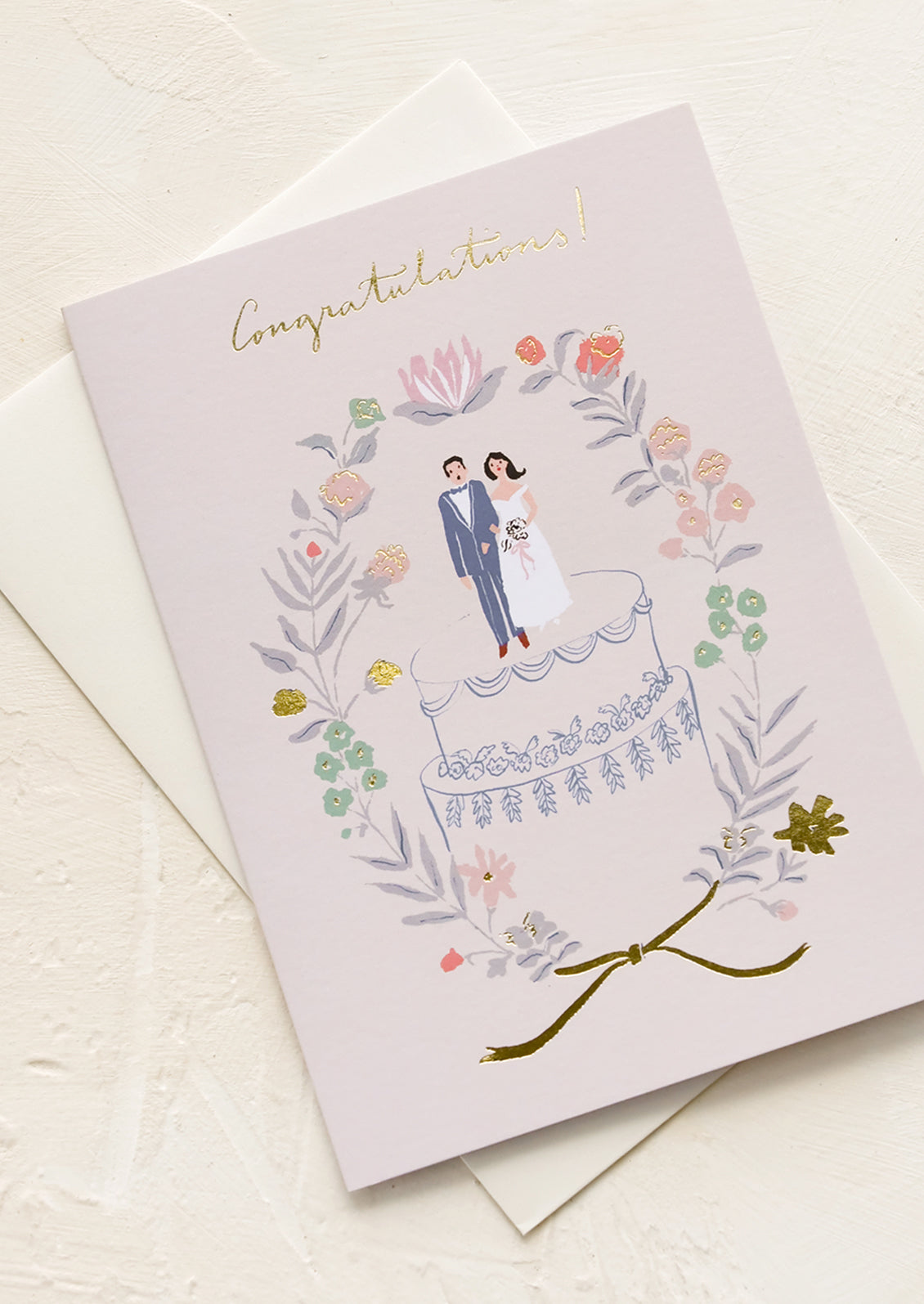 A greeting card with illustration of man and woman on top of a wedding cake.