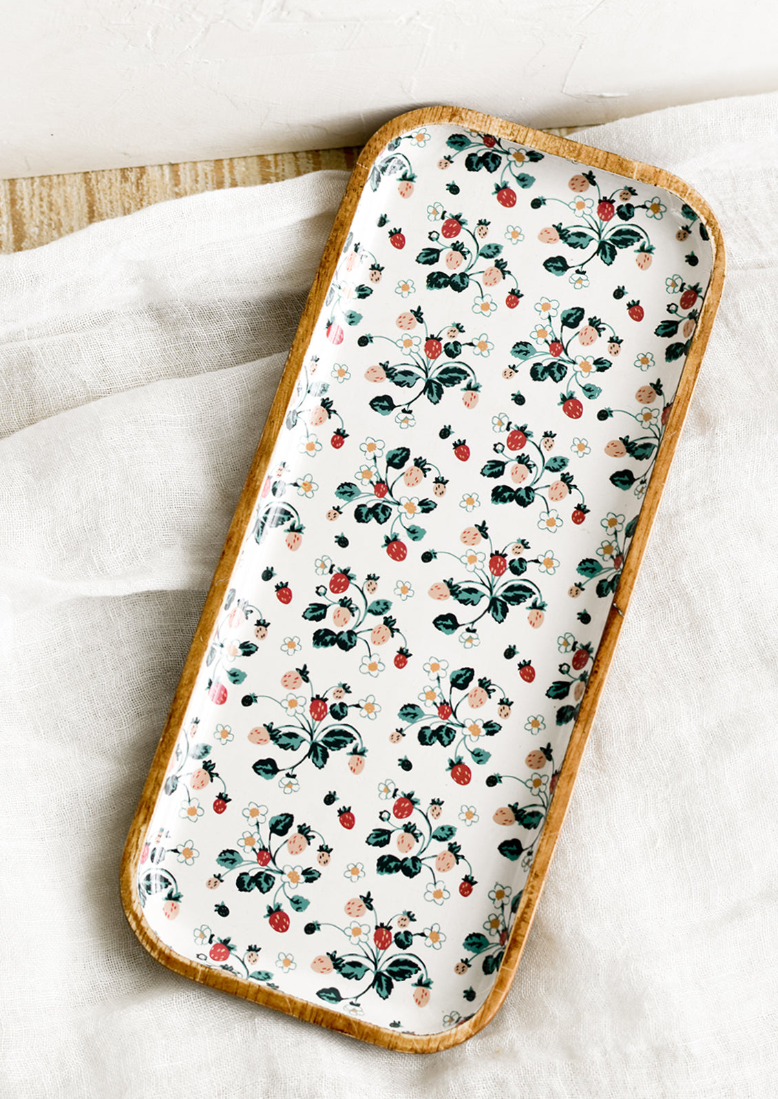 A rectangular wooden tray with white strawberry enamel pattern.