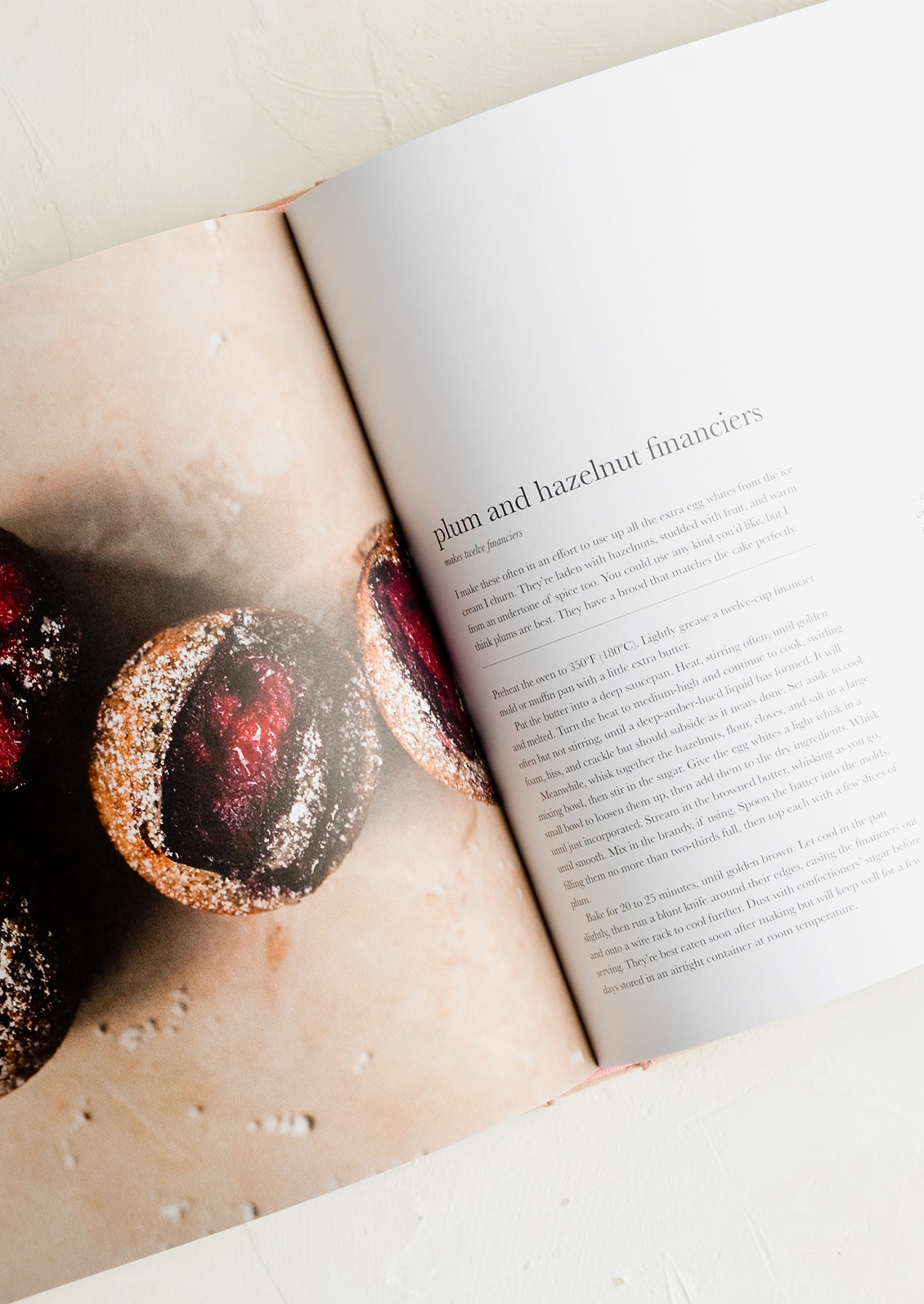 A recipe cookbook opened to recipe for plum and hazelnut financiers.