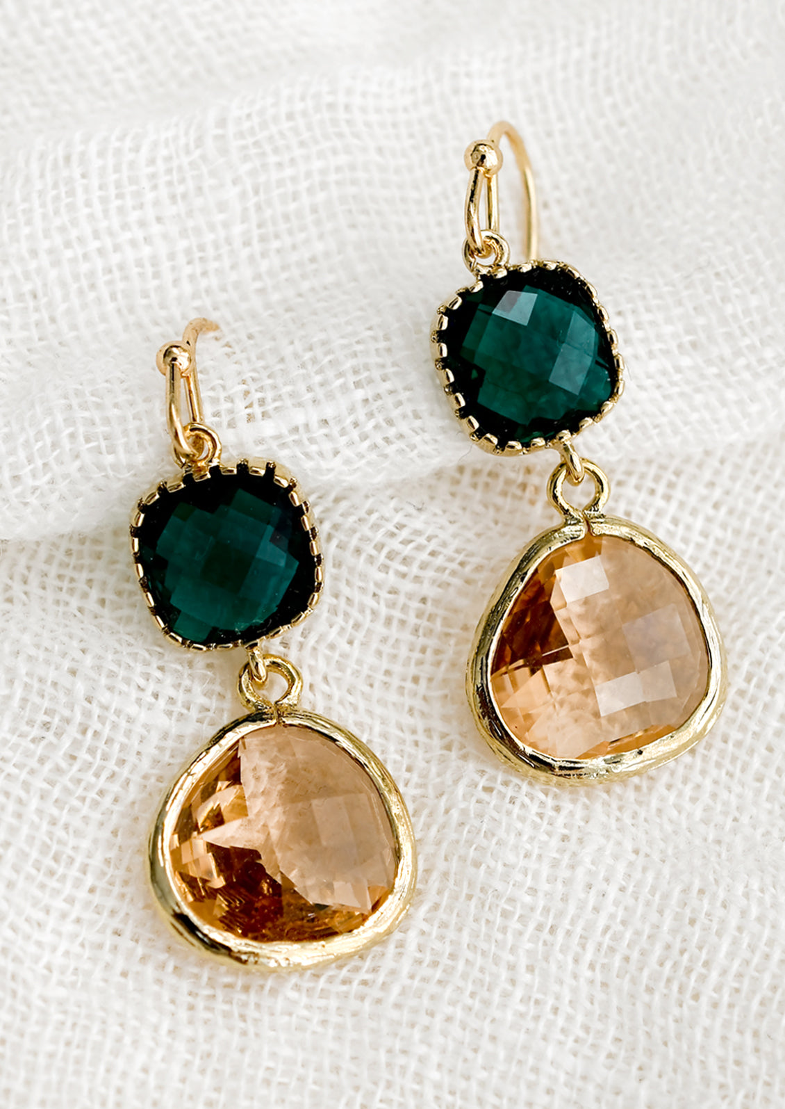 A pair of two-stone bezeled gem earrings in emerald and blush.